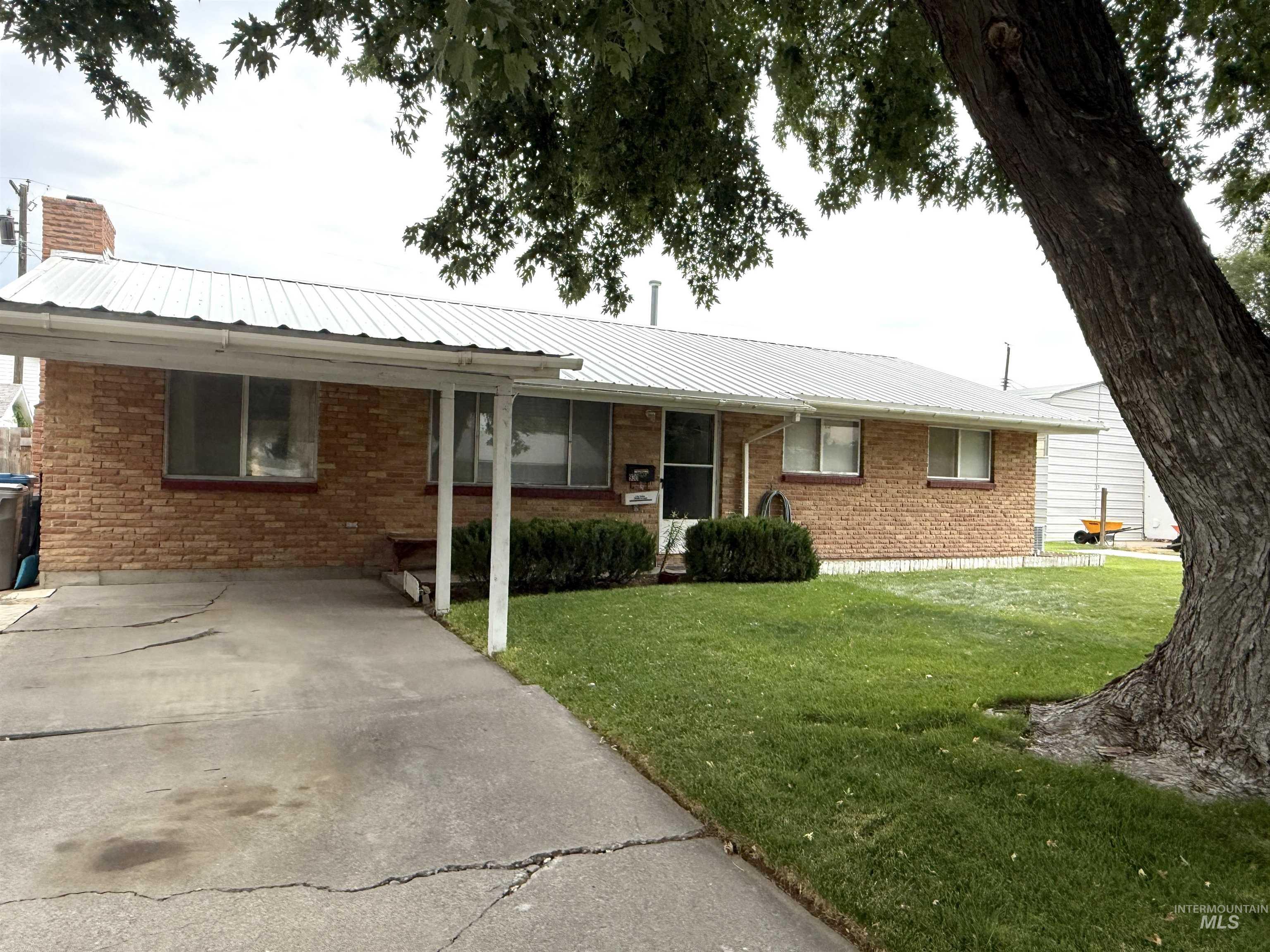 Ranch-style home featuring a front yard, a metal roof, and brick siding