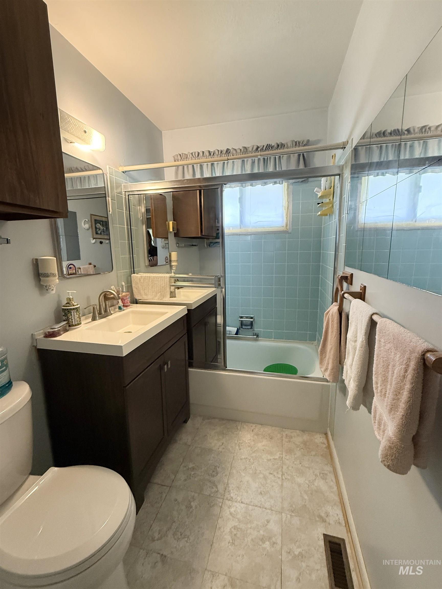 Bathroom featuring shower / bath combination with glass door, vanity, and light tile patterned flooring