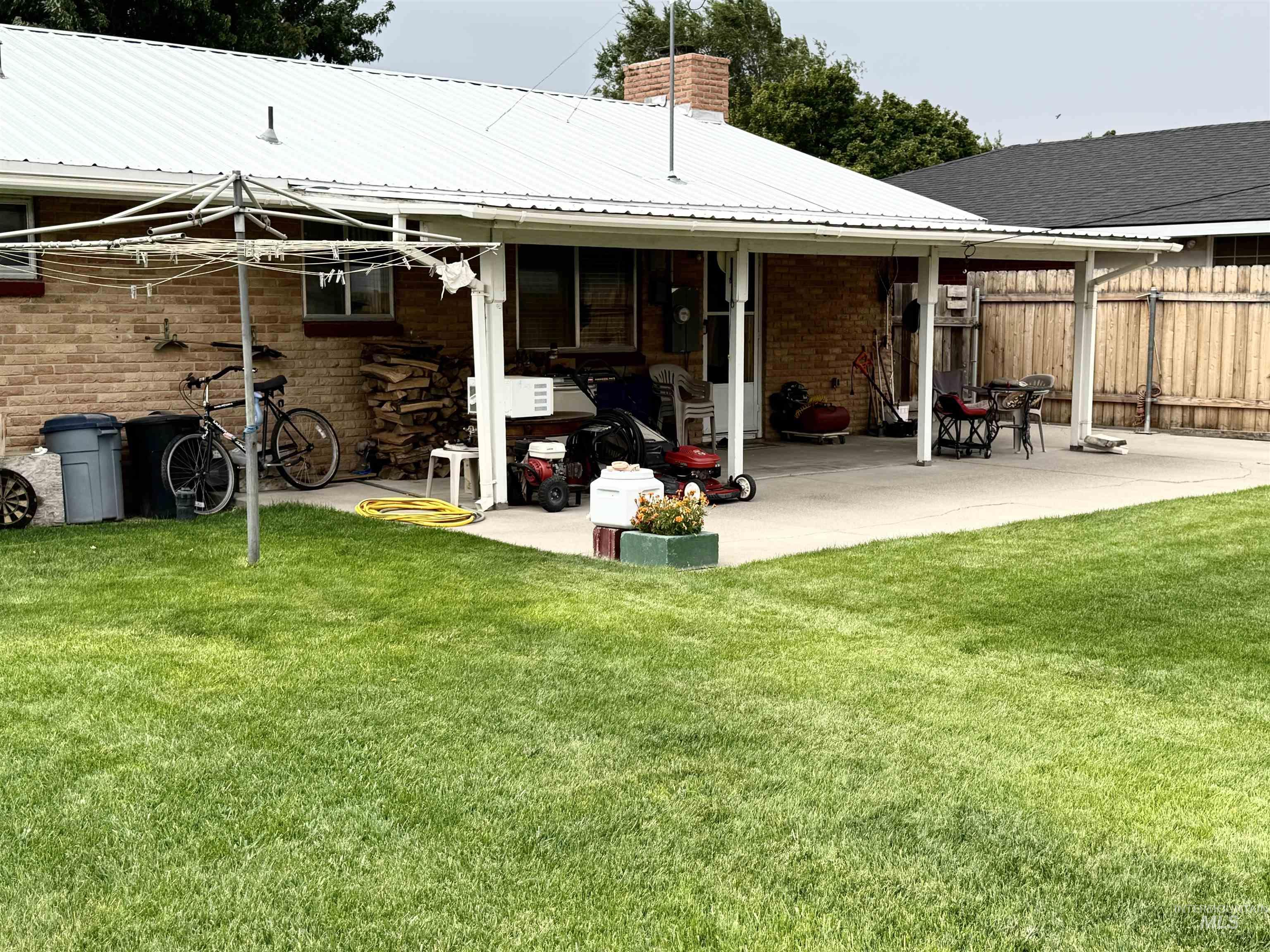 Back of property featuring a chimney, a patio, a metal roof, and brick siding