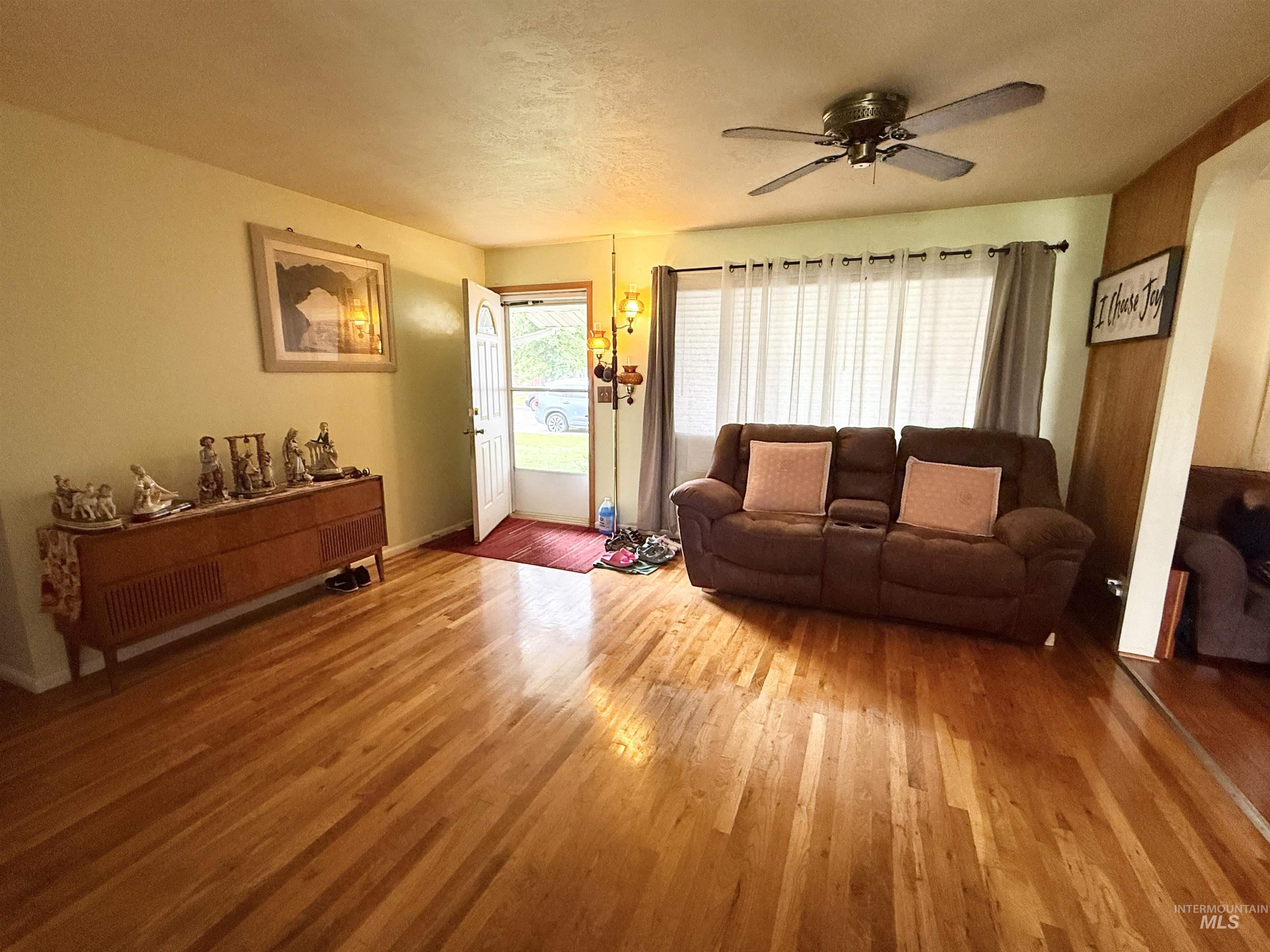 Living area with wood finished floors, a ceiling fan, and a textured ceiling
