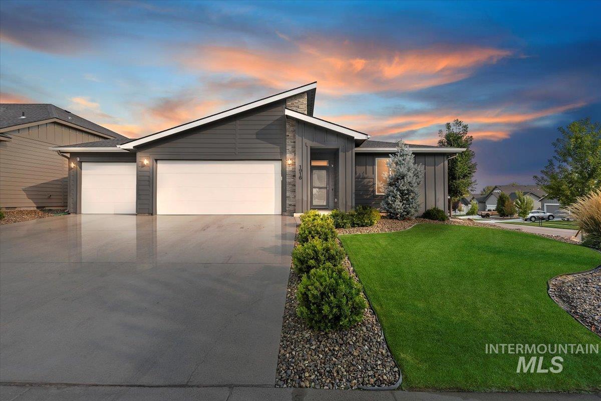 Mid-century inspired home with board and batten siding, driveway, a garage, a lawn, and stone siding