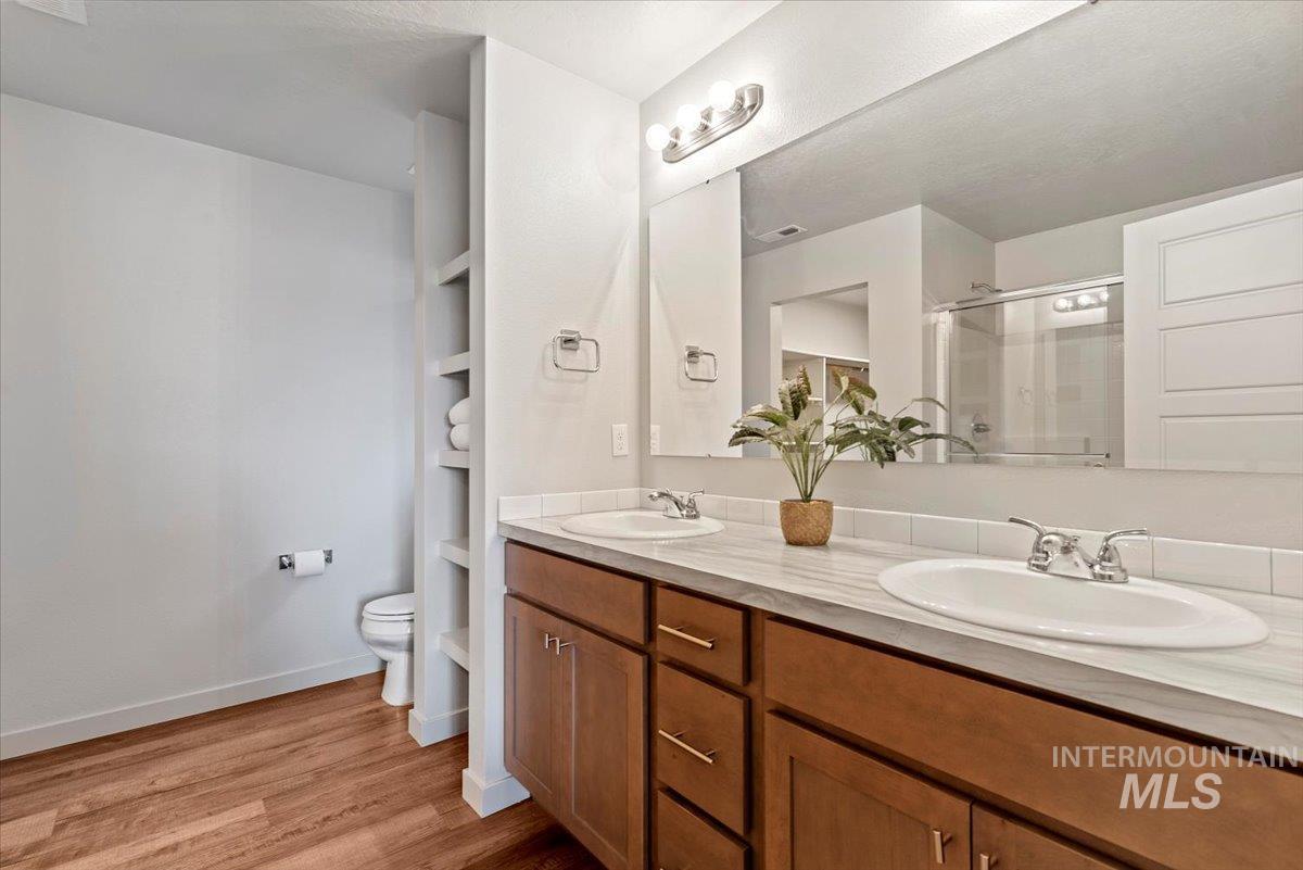 Bathroom featuring a shower stall, light wood-style floors, and double vanity