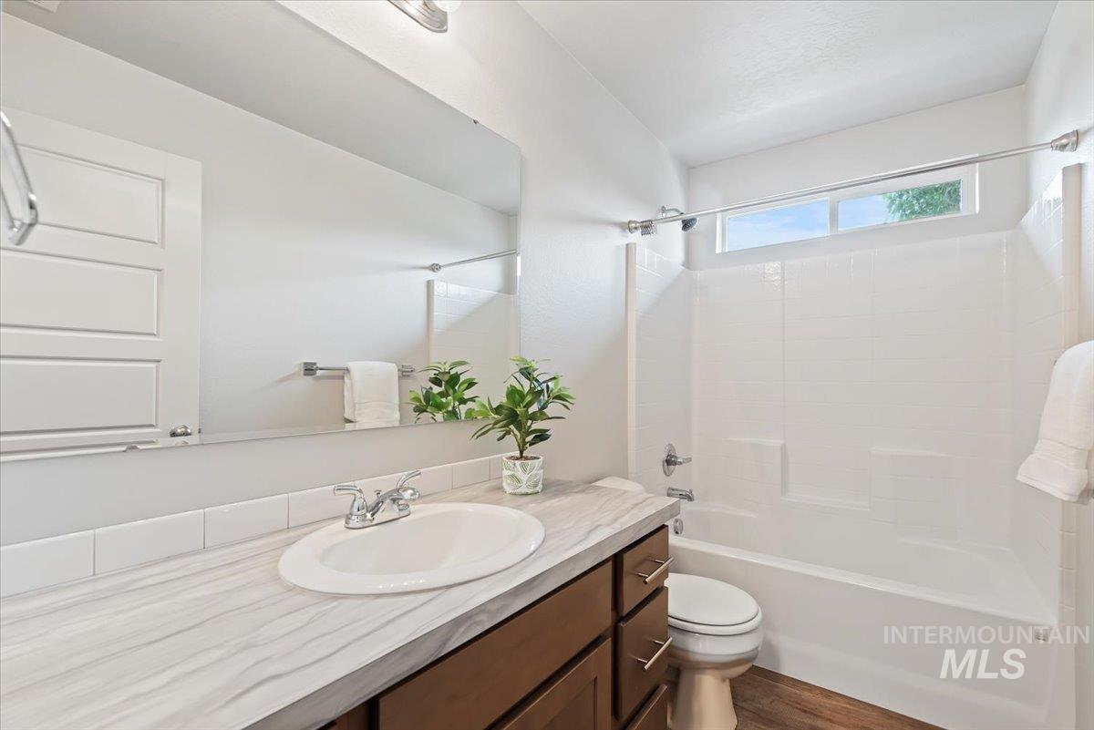 Bathroom with tub / shower combination, vanity, and dark wood-type flooring