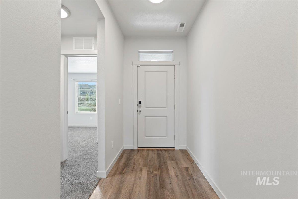Doorway to outside with vinyl plank finished floors and a textured wall