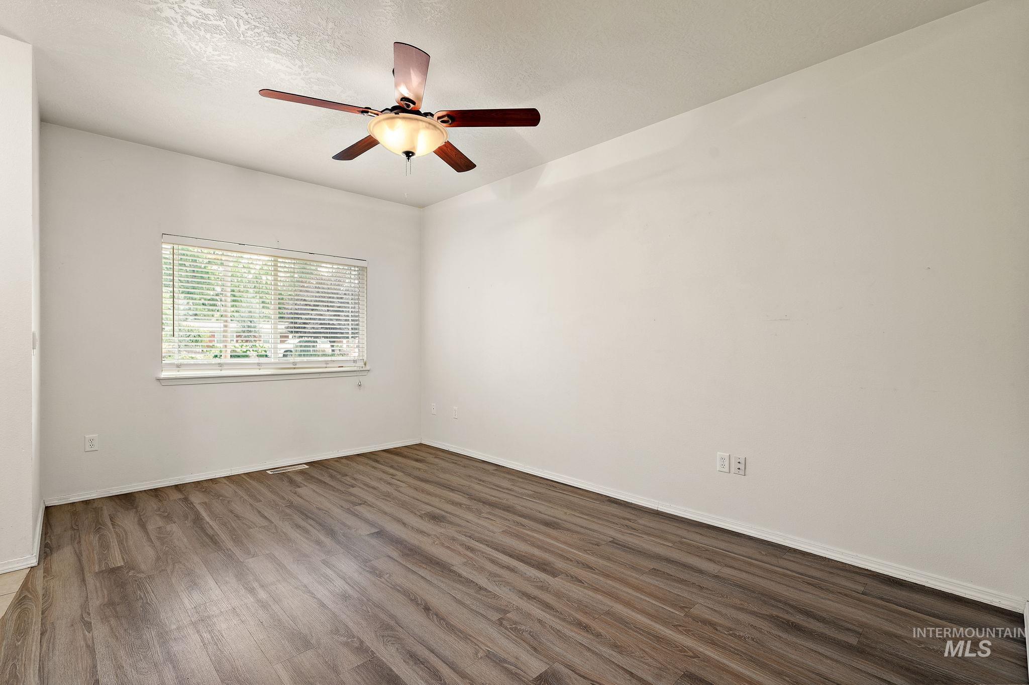 Spare room featuring wood finished floors, a textured ceiling, and ceiling fan