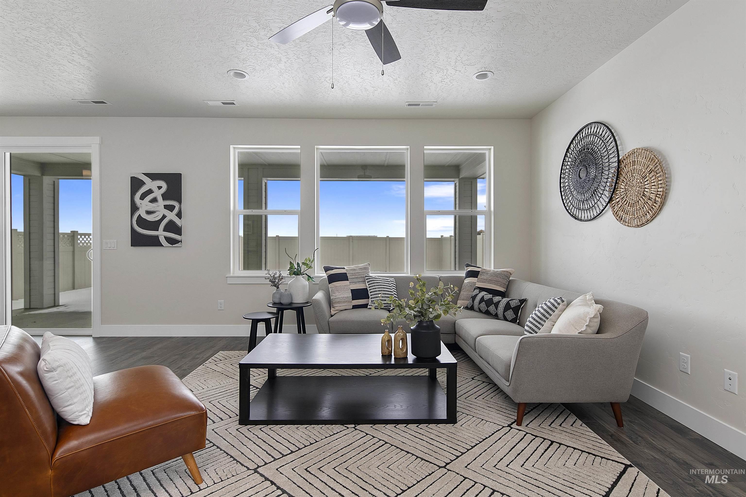 Living area with a textured ceiling, wood finished floors, and ceiling fan