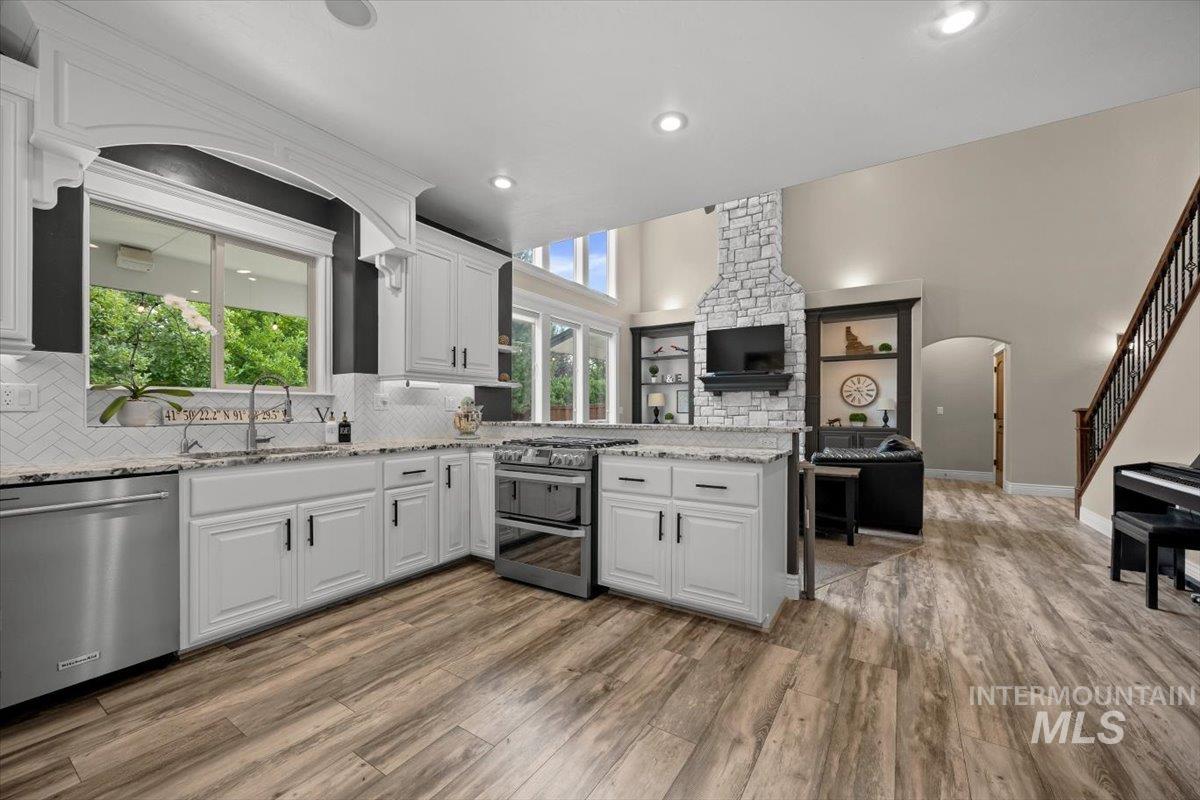 Kitchen with light stone countertops, open floor plan, appliances with stainless steel finishes, a peninsula, and arched walkways