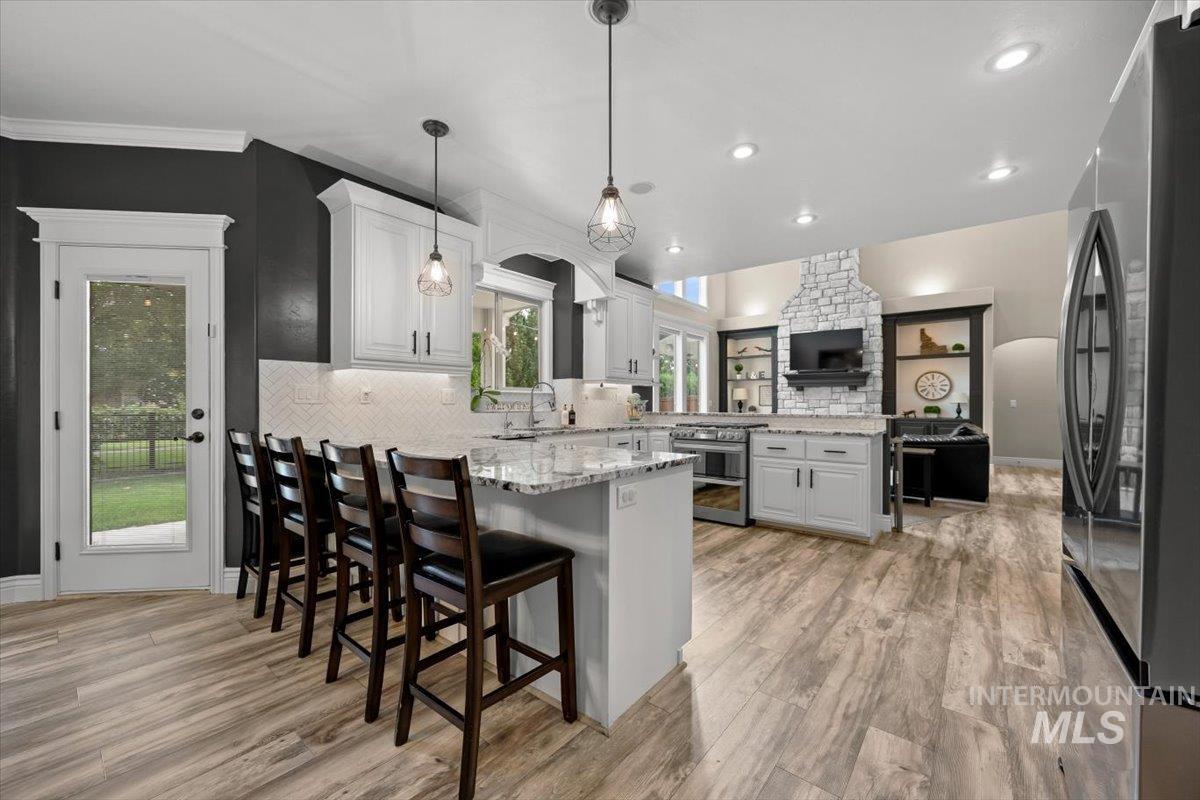 Kitchen featuring a peninsula, open floor plan, arched walkways, light stone counters, and appliances with stainless steel finishes