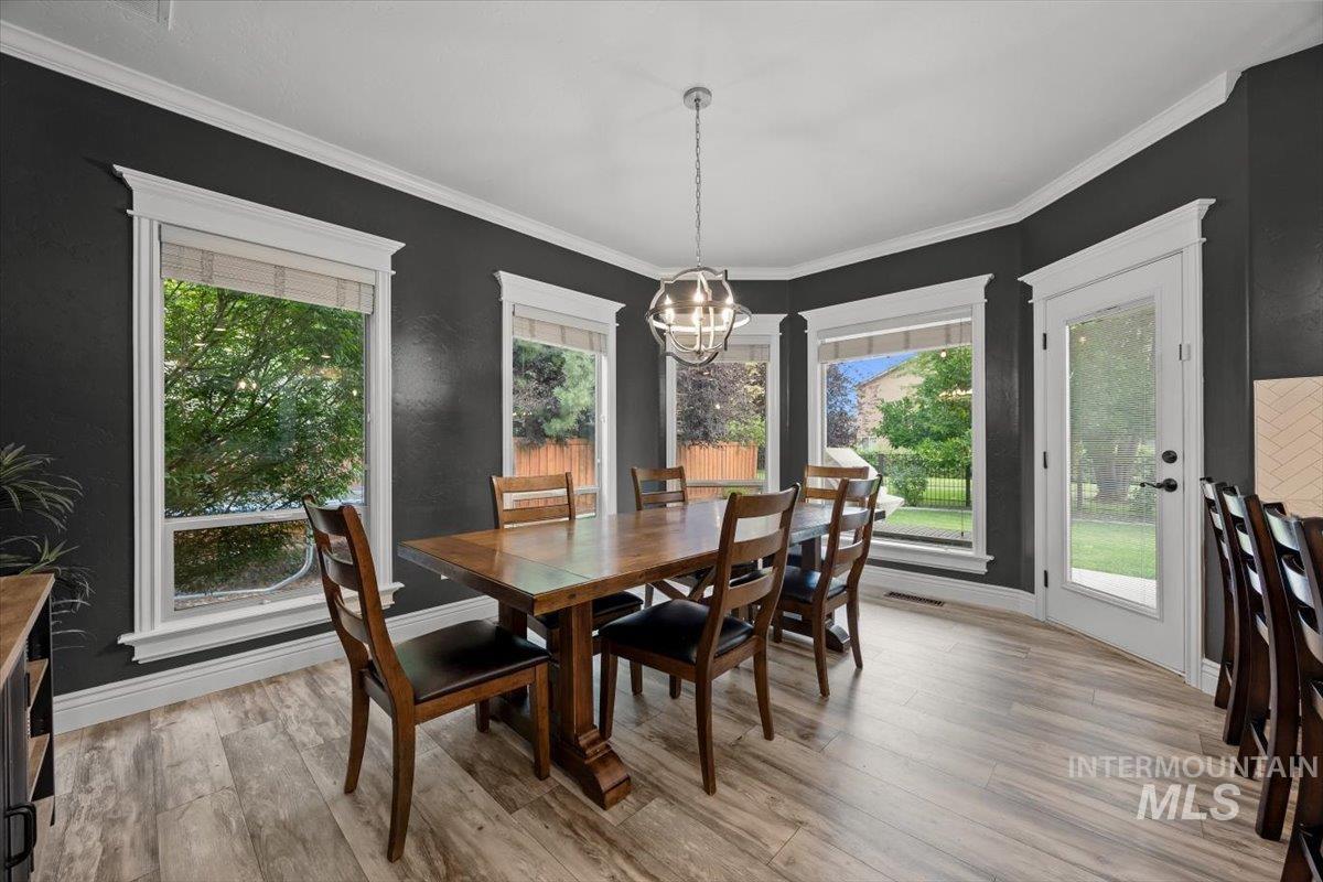 Dining room with light wood-style flooring, crown molding, and a chandelier
