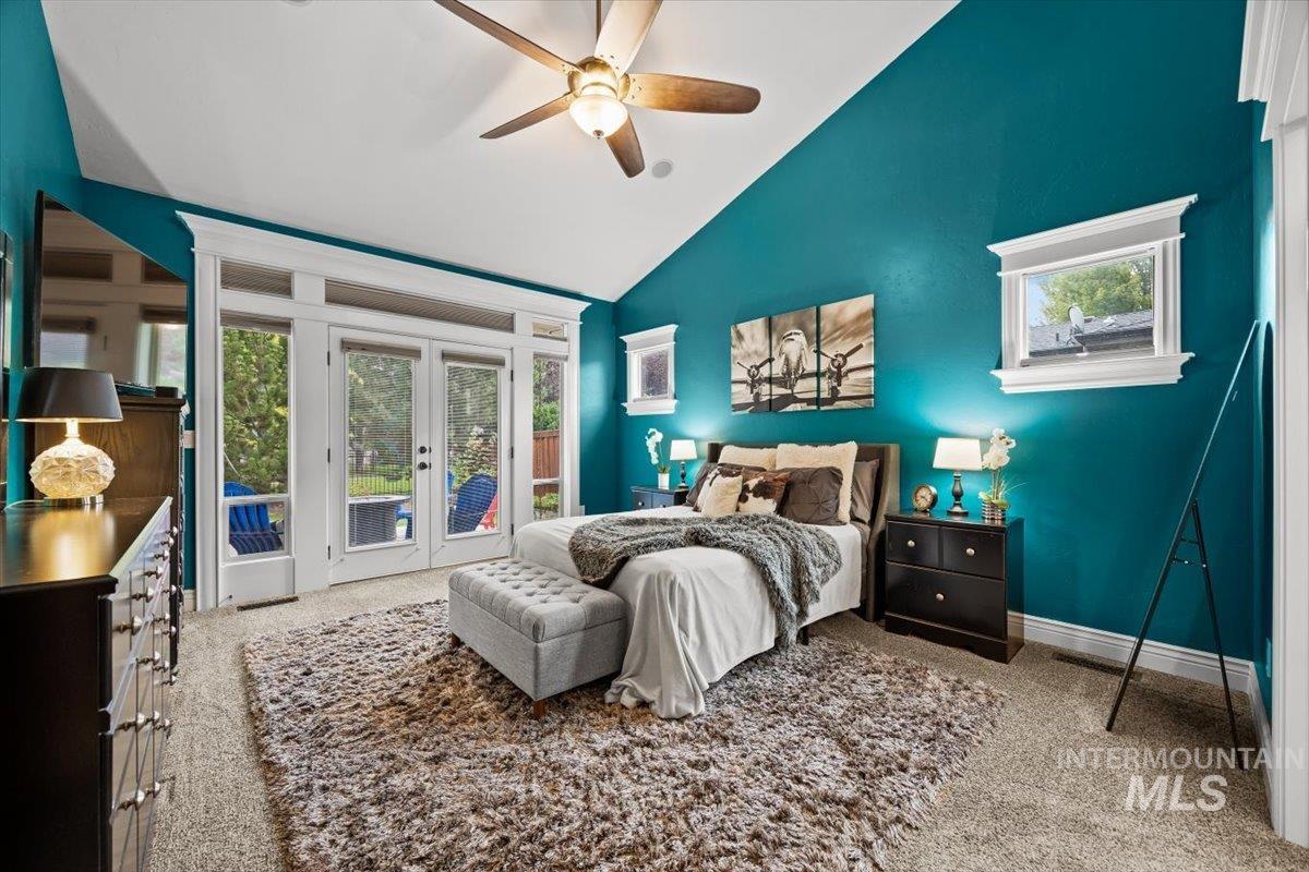 Bedroom with multiple windows, high vaulted ceiling, light carpet, and access to outside