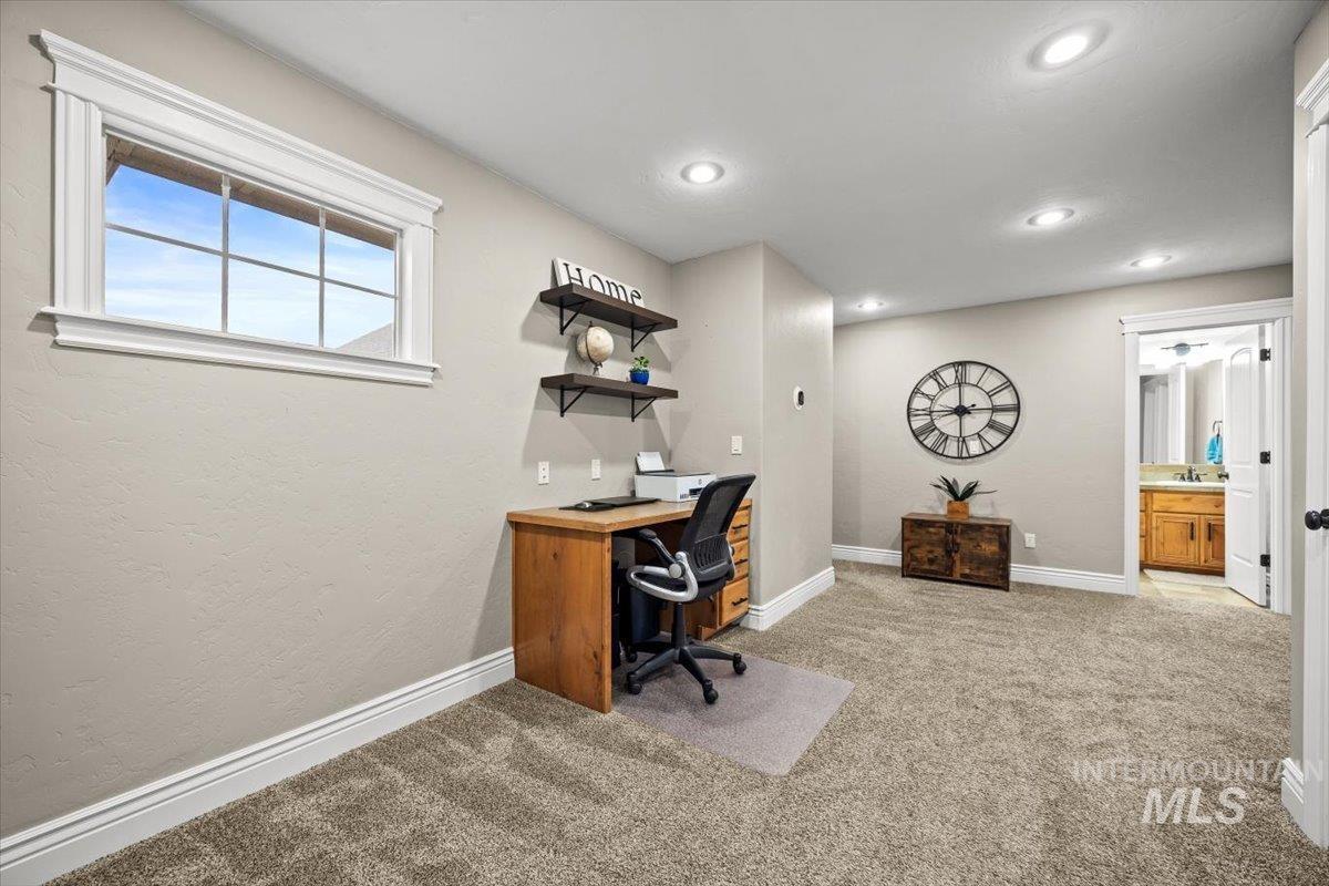 Loft area with light carpet, a textured wall, and recessed lighting