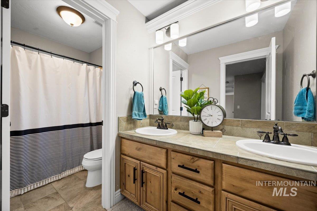 Full bath featuring double vanity and curtained shower