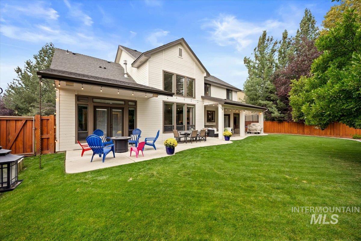 Rear view of house with a patio area, a fenced backyard, roof with shingles, and a fire pit