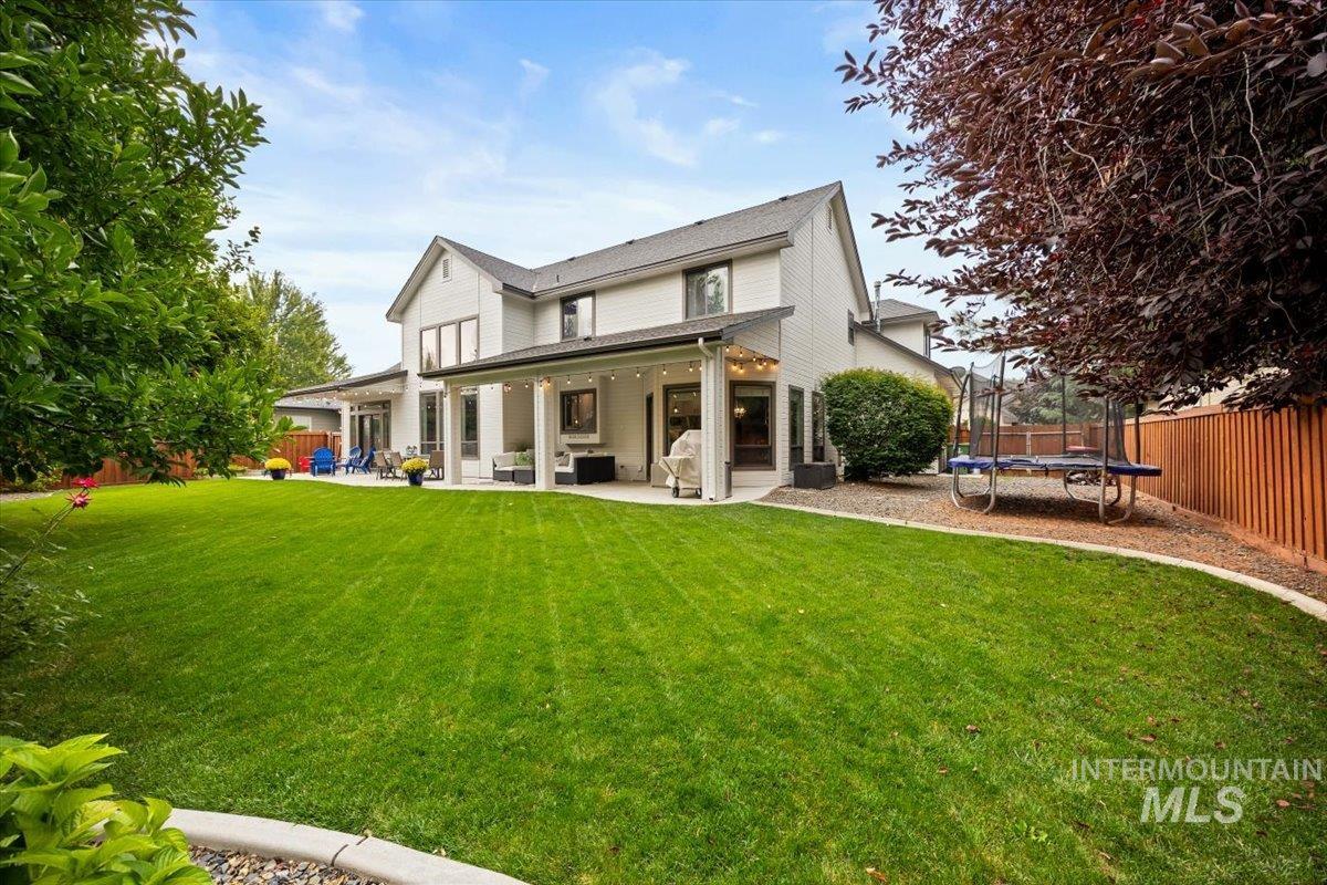 Back of house featuring a trampoline, a patio area, and a fenced backyard