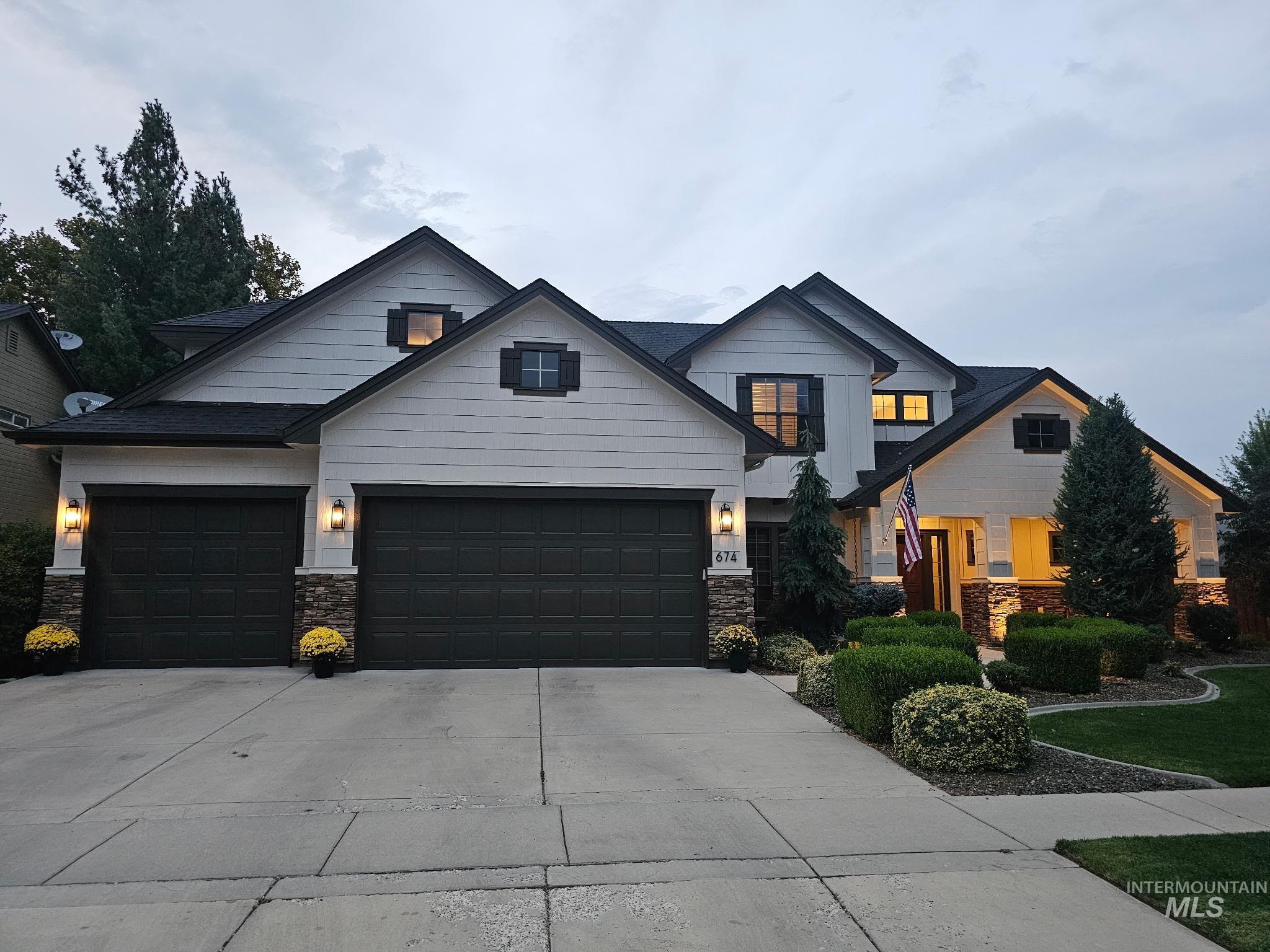 View of front facade featuring driveway, stone siding, and a garage