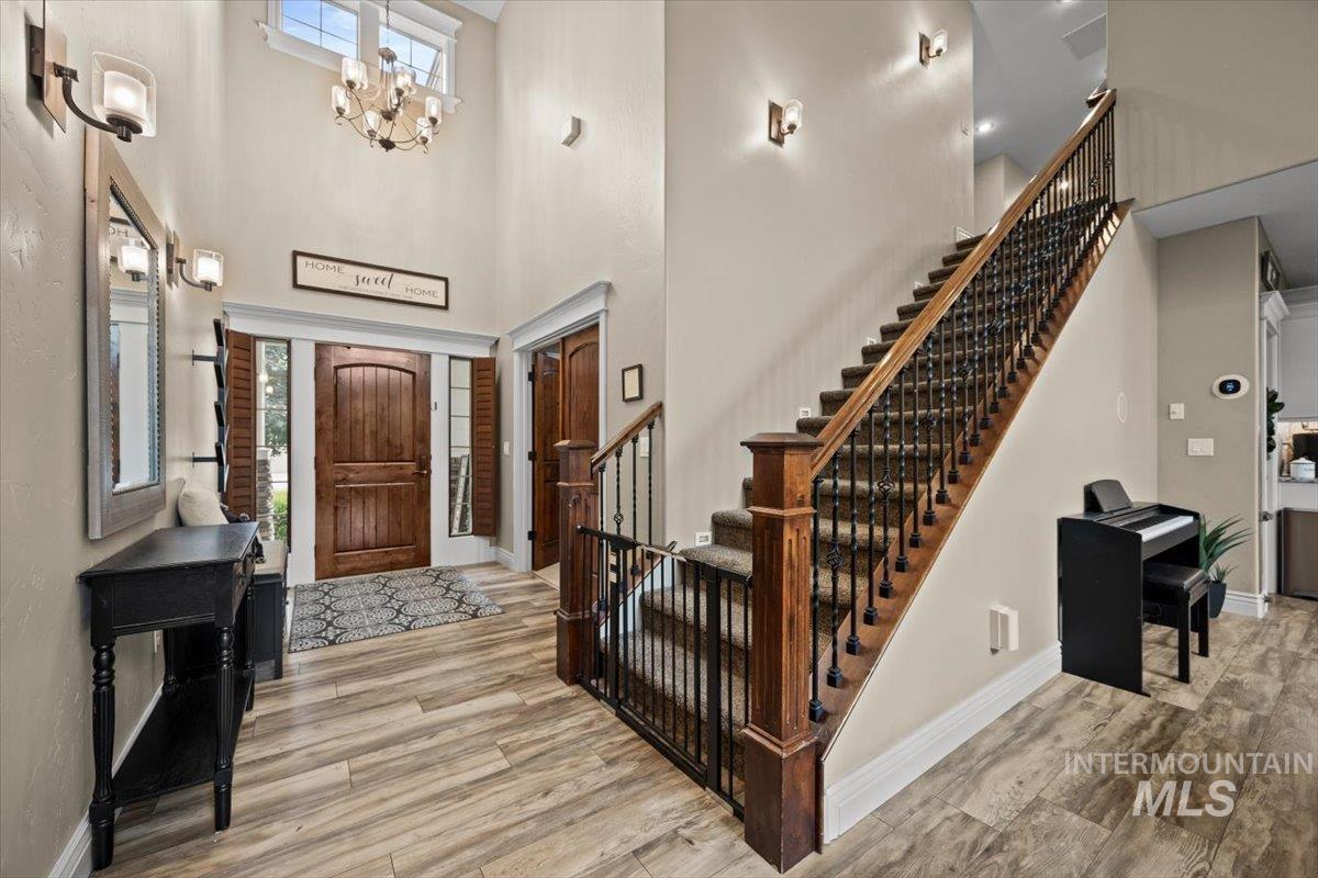 Entrance foyer with light wood finished floors, a towering ceiling, and a chandelier