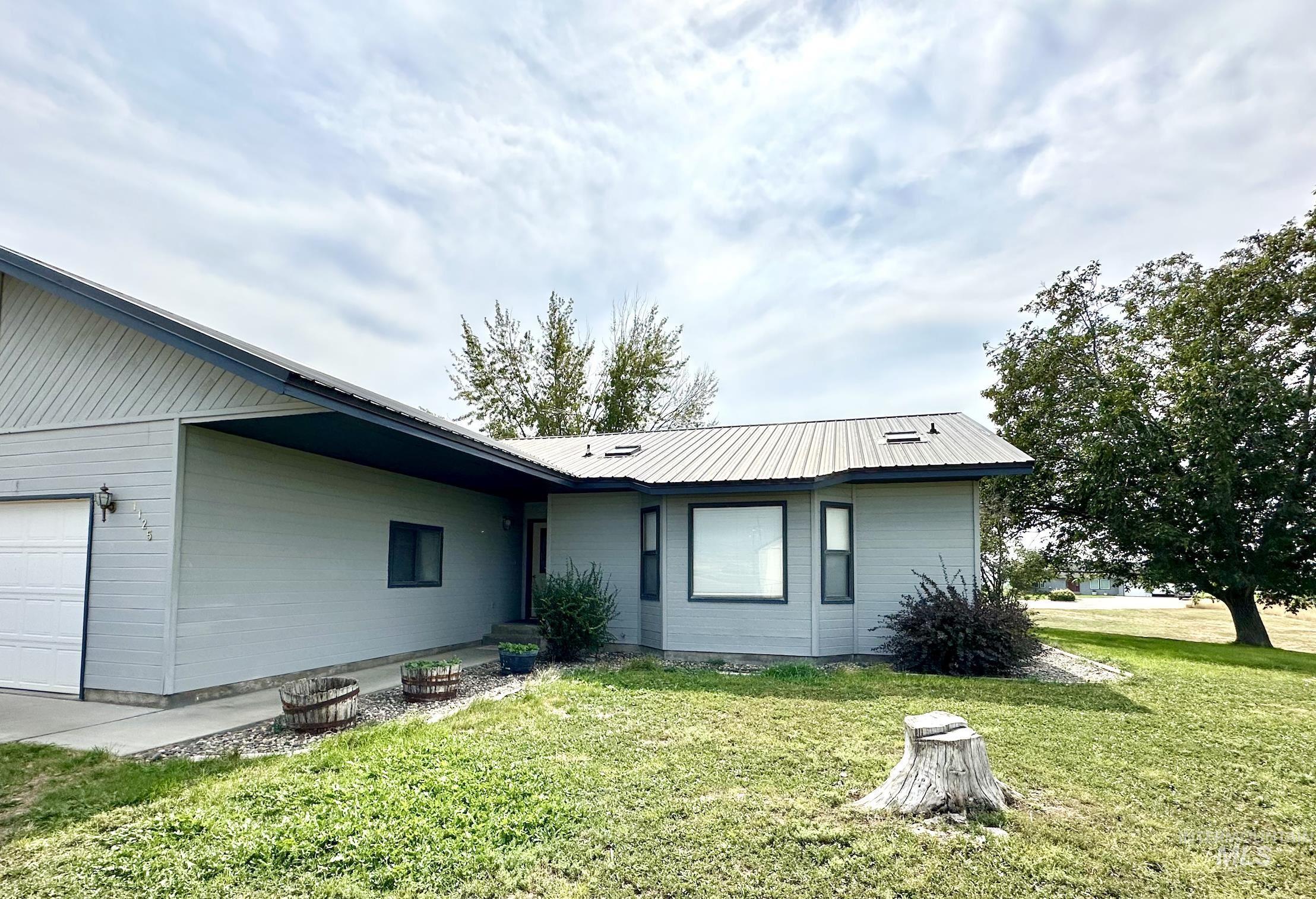 Rear view of house with a yard, an attached garage, and a metal roof