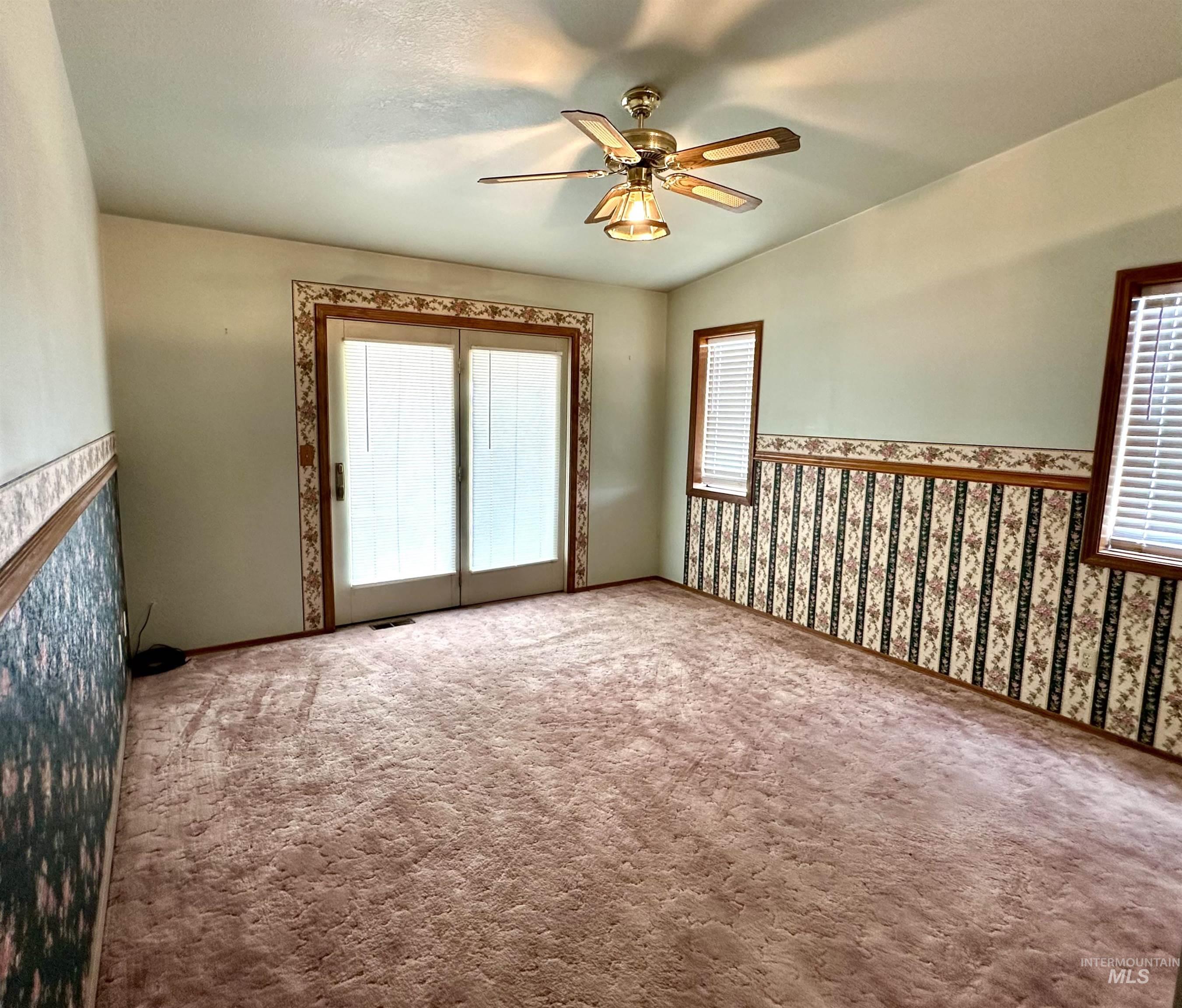 Spare room with carpet, plenty of natural light, ceiling fan, and wallpapered walls