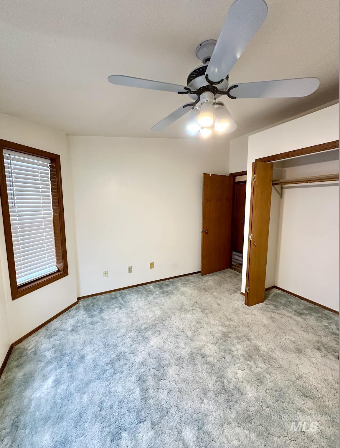 Unfurnished bedroom with a ceiling fan, light carpet, and a closet