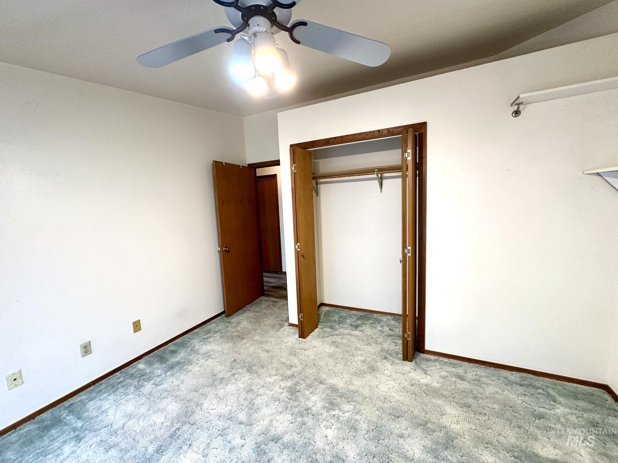 Unfurnished bedroom featuring a closet, a ceiling fan, and light carpet