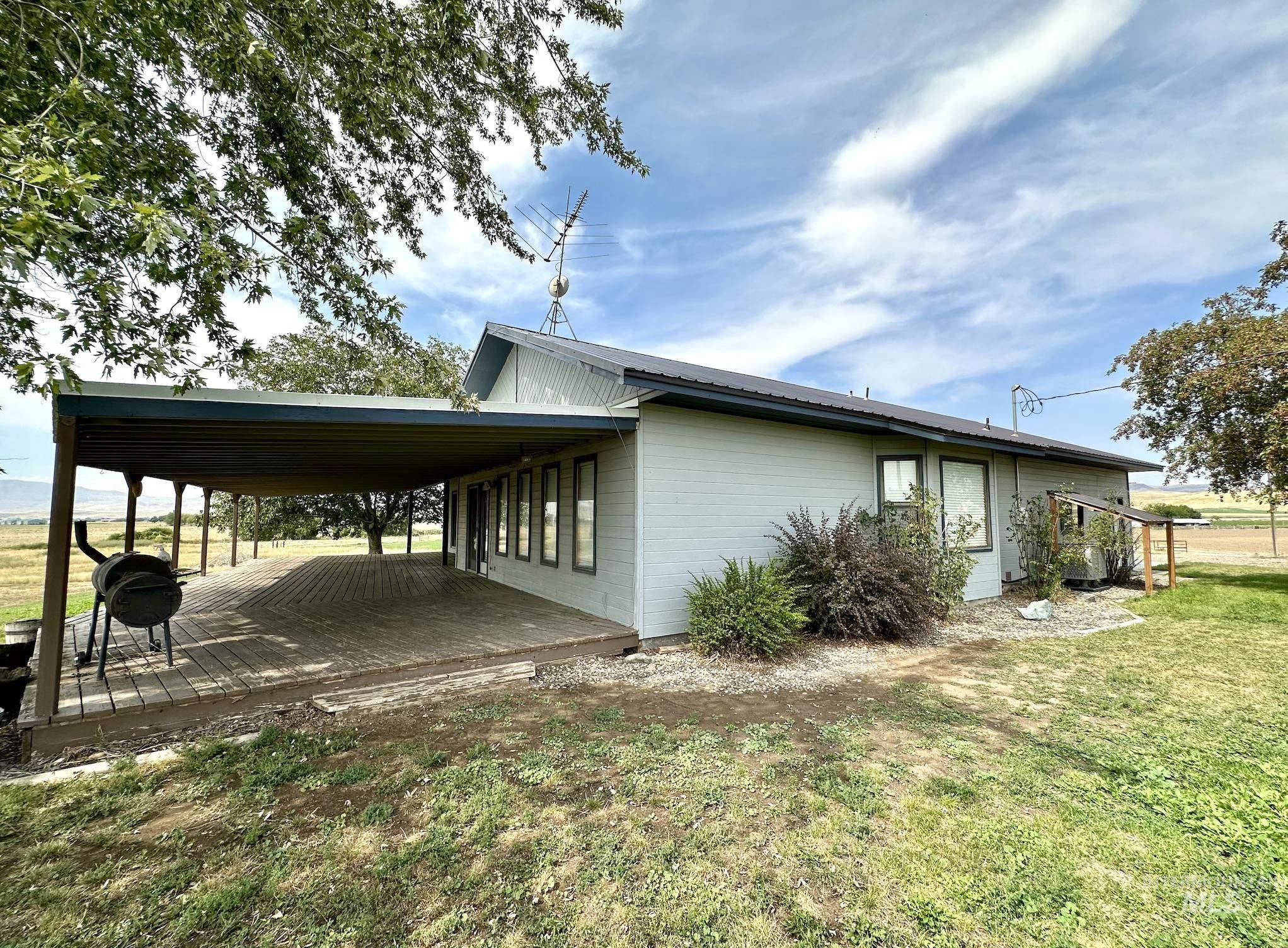 View of side of home with a lawn, a wooden deck, a carport, and a metal roof