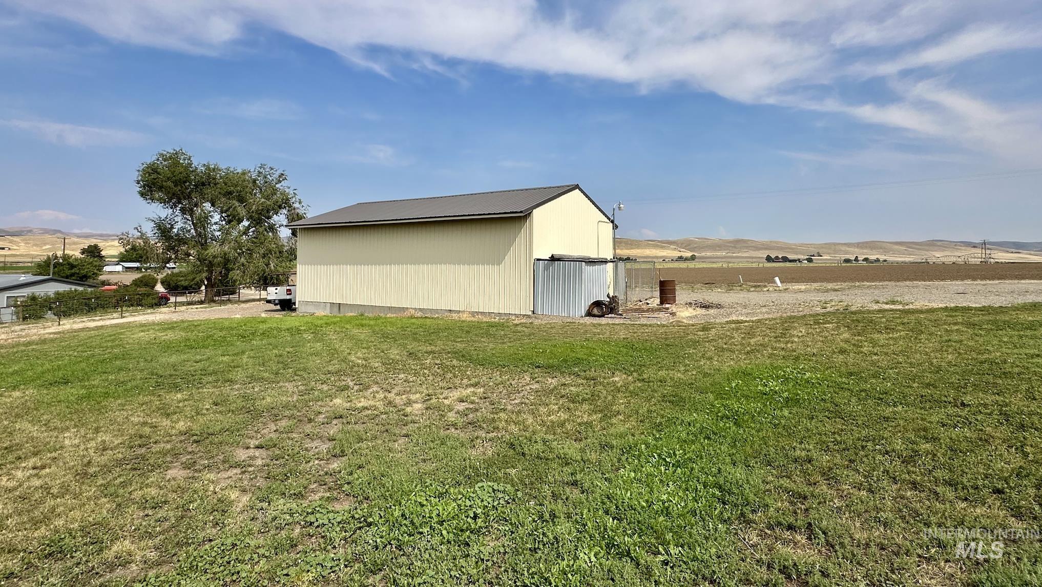 View of side of property featuring an outdoor structure, an outbuilding, a view of countryside, a mountain view, and a metal roof