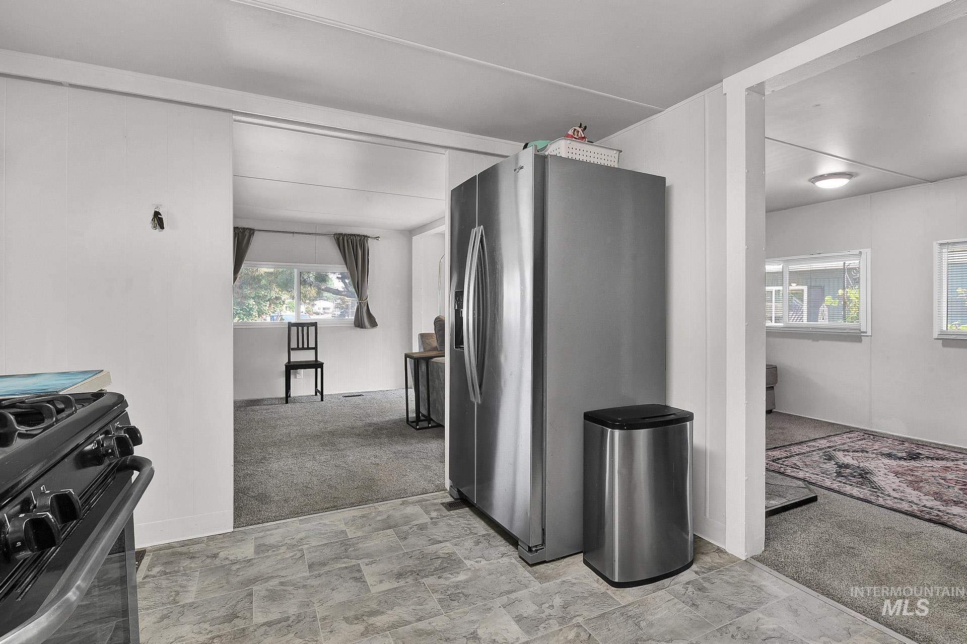 Corridor featuring light colored carpet, healthy amount of natural light, and stone finish floors