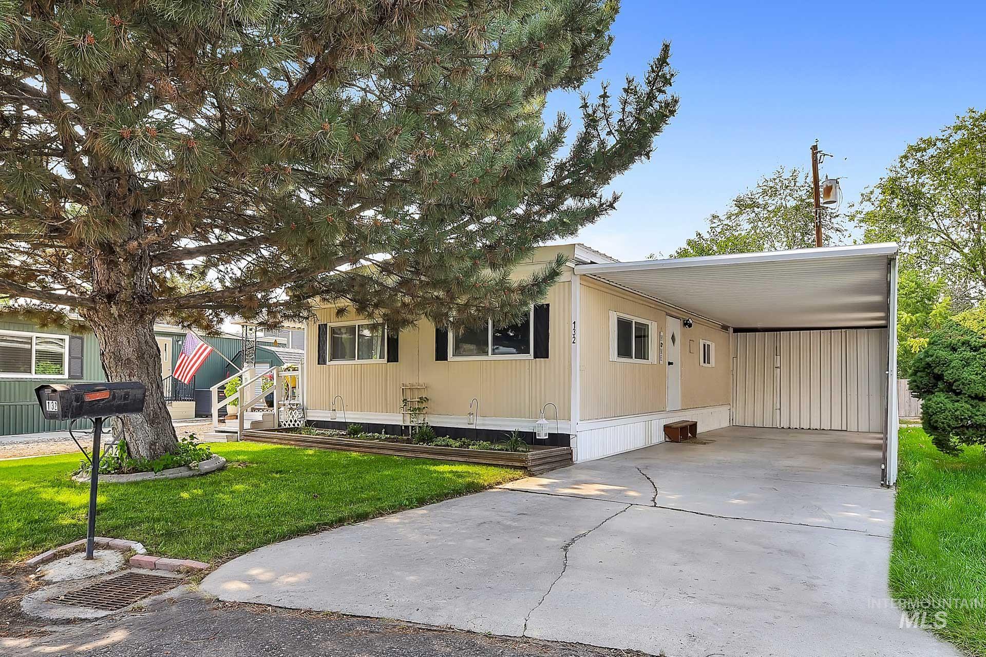 Manufactured / mobile home with concrete driveway, an attached carport, and a front yard