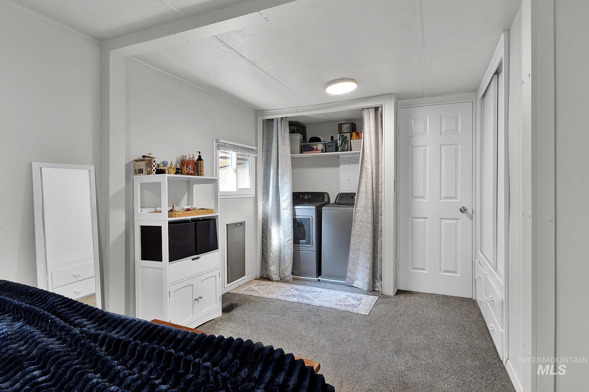 Bedroom featuring light colored carpet and independent washer and dryer