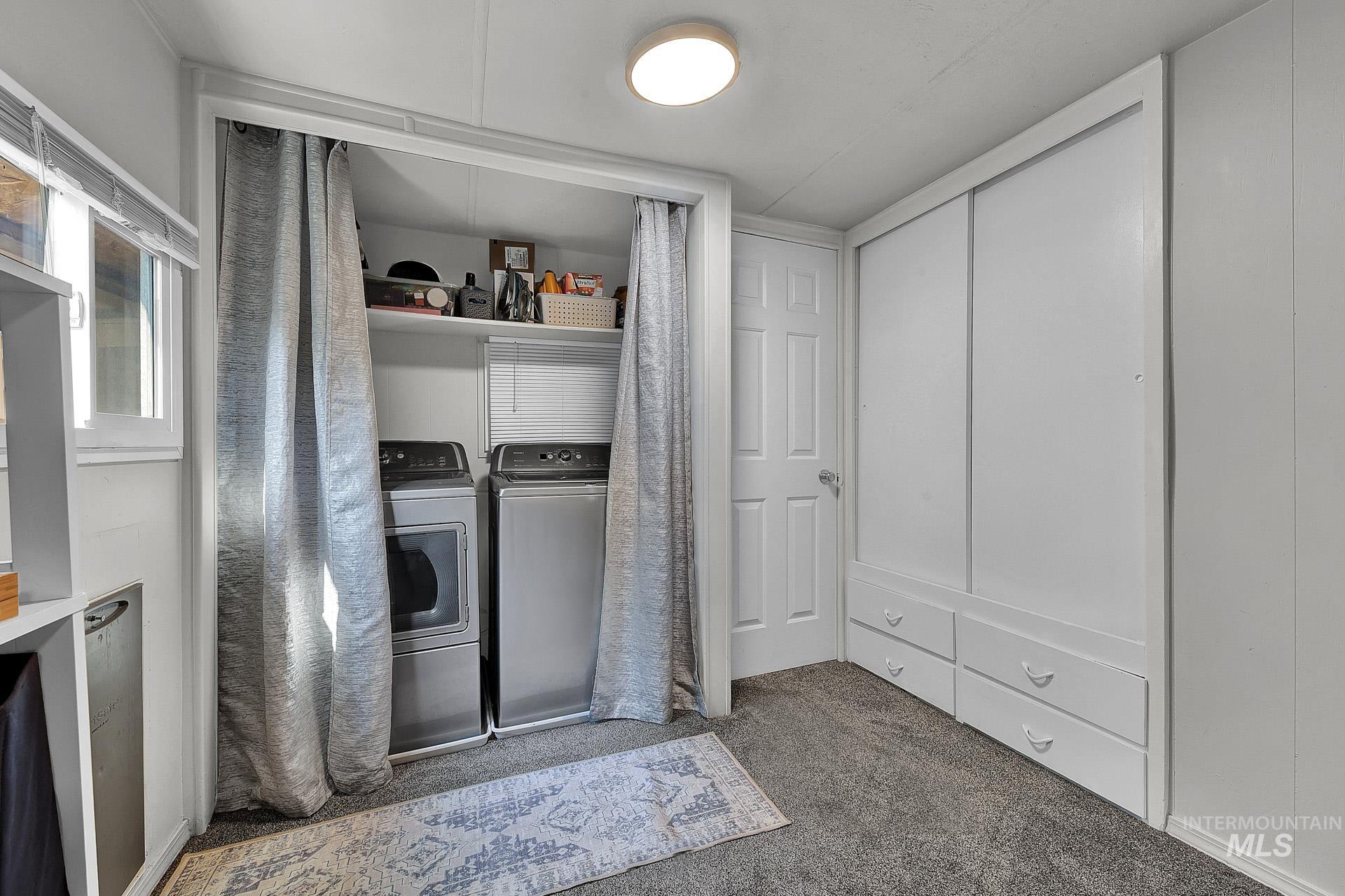 Washroom featuring dark colored carpet and washer and dryer