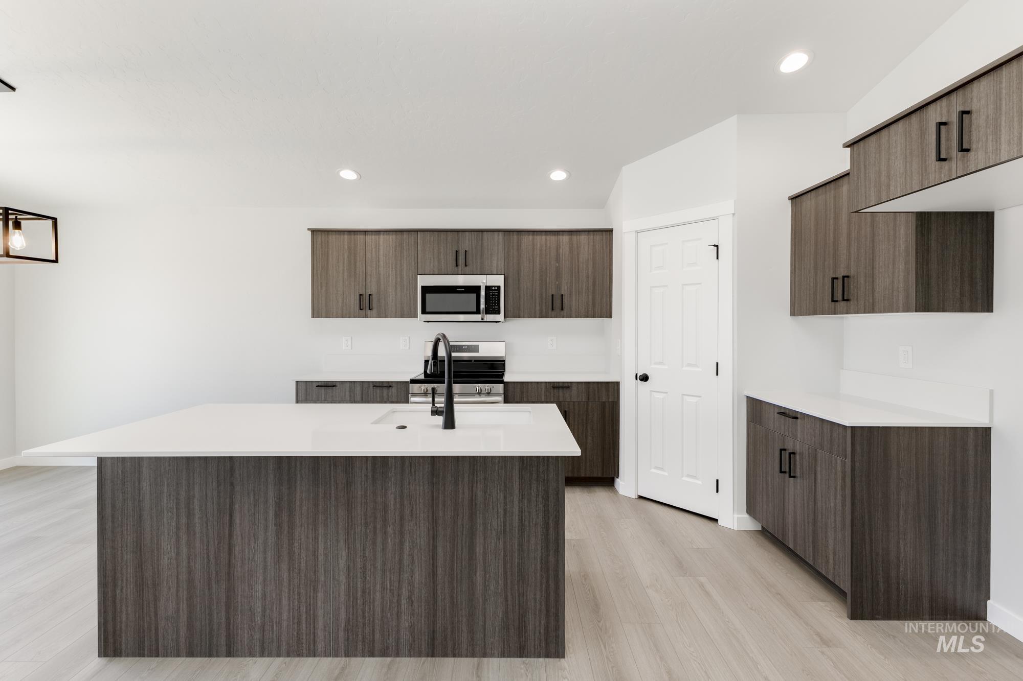Kitchen with light countertops, recessed lighting, stainless steel appliances, modern cabinets, and dark brown cabinetry