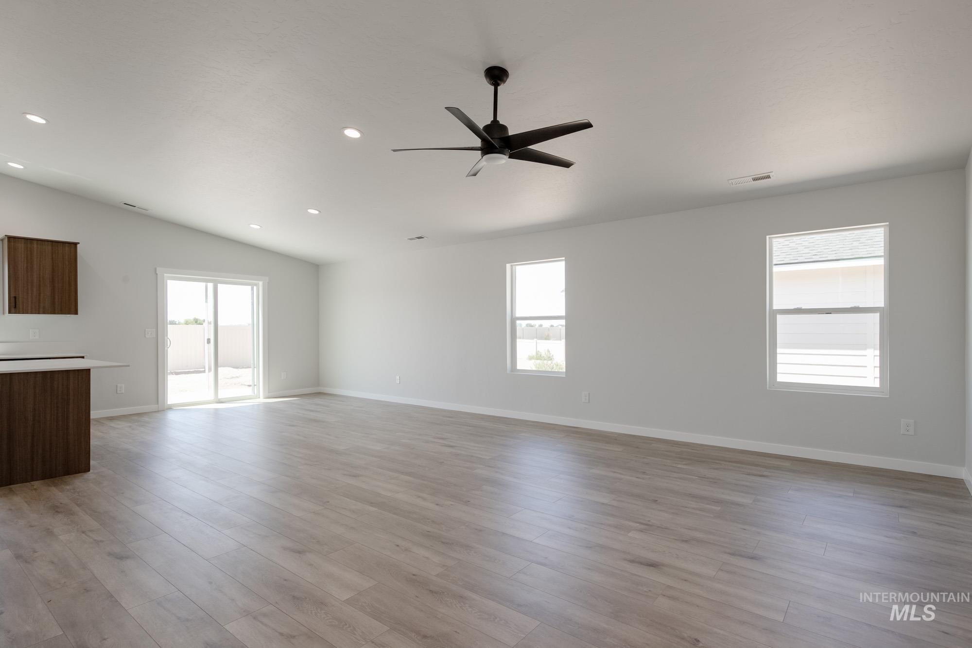 Unfurnished living room featuring ceiling fan, vaulted ceiling, recessed lighting, and light wood finished floors