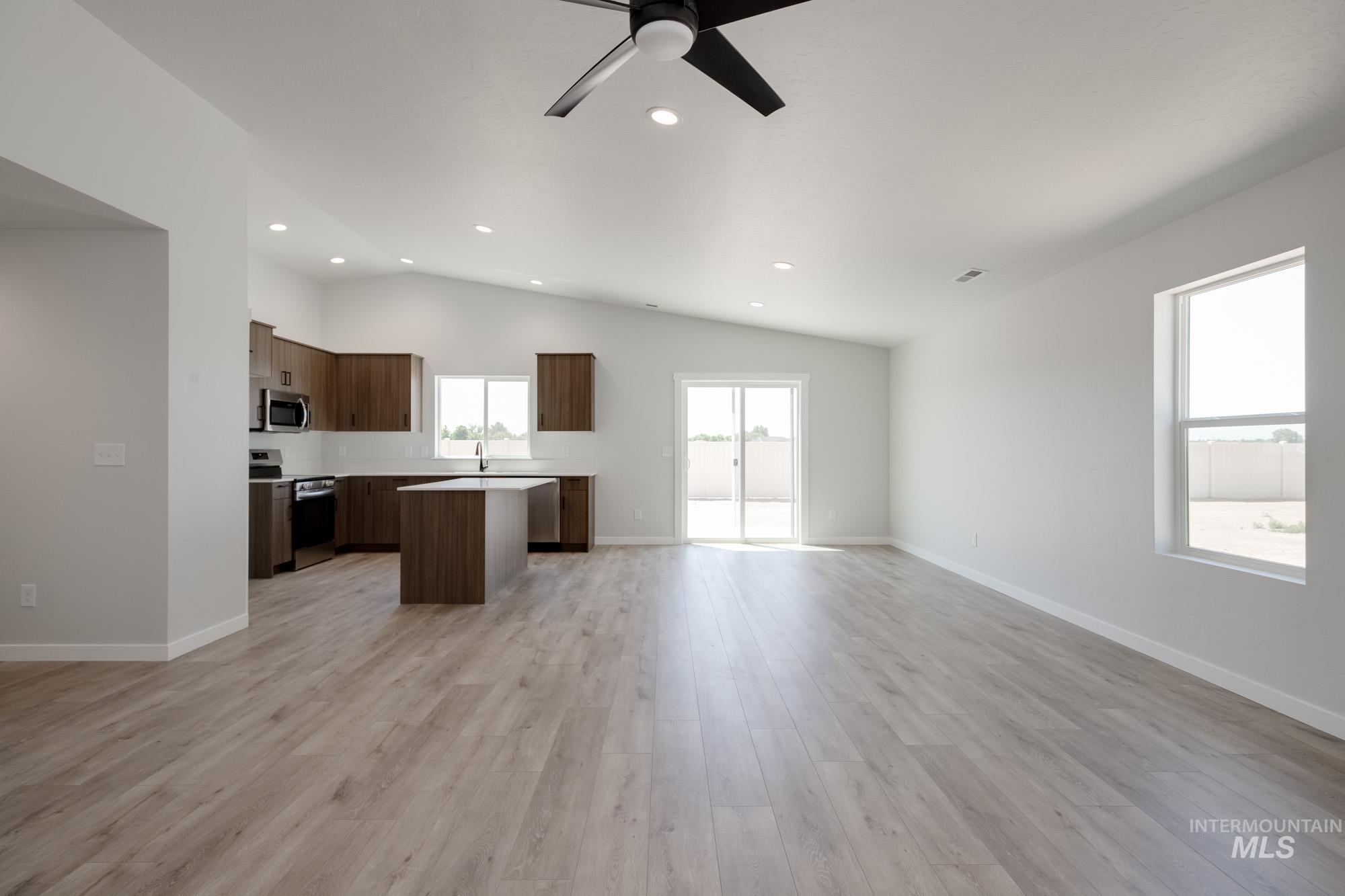 Unfurnished living room with lofted ceiling, recessed lighting, light wood-type flooring, and a ceiling fan