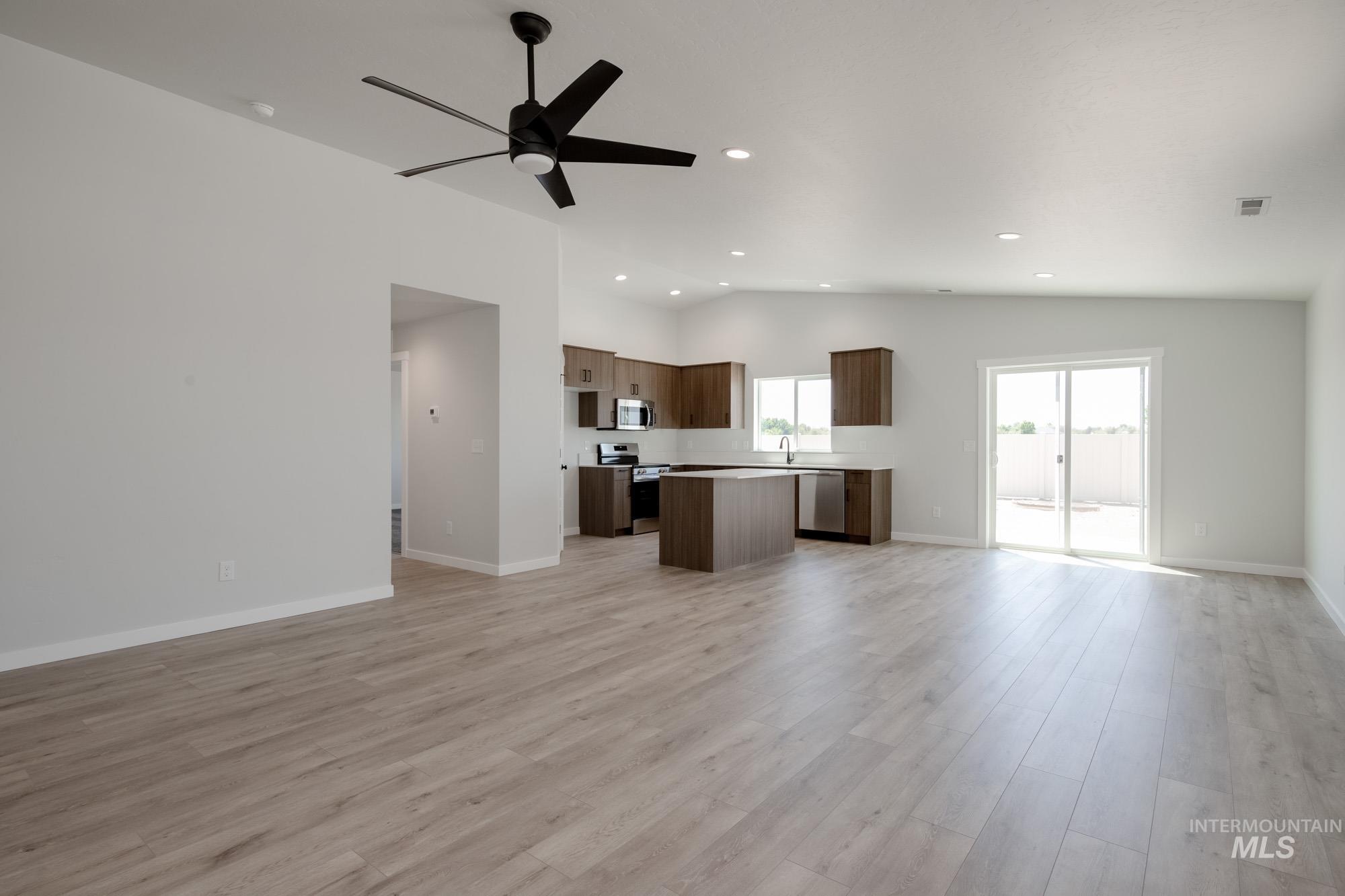 Unfurnished living room with vaulted ceiling, recessed lighting, ceiling fan, and light wood finished floors