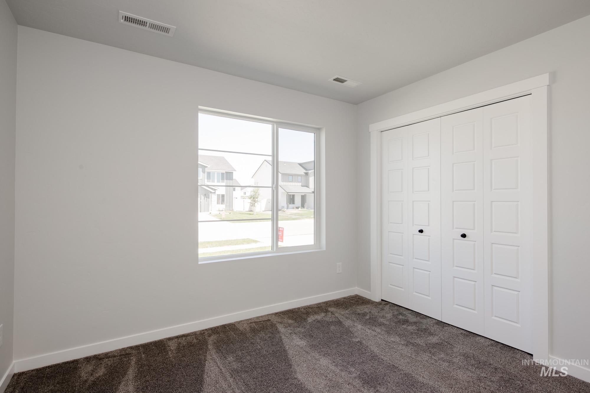 Unfurnished bedroom featuring dark carpet and a closet