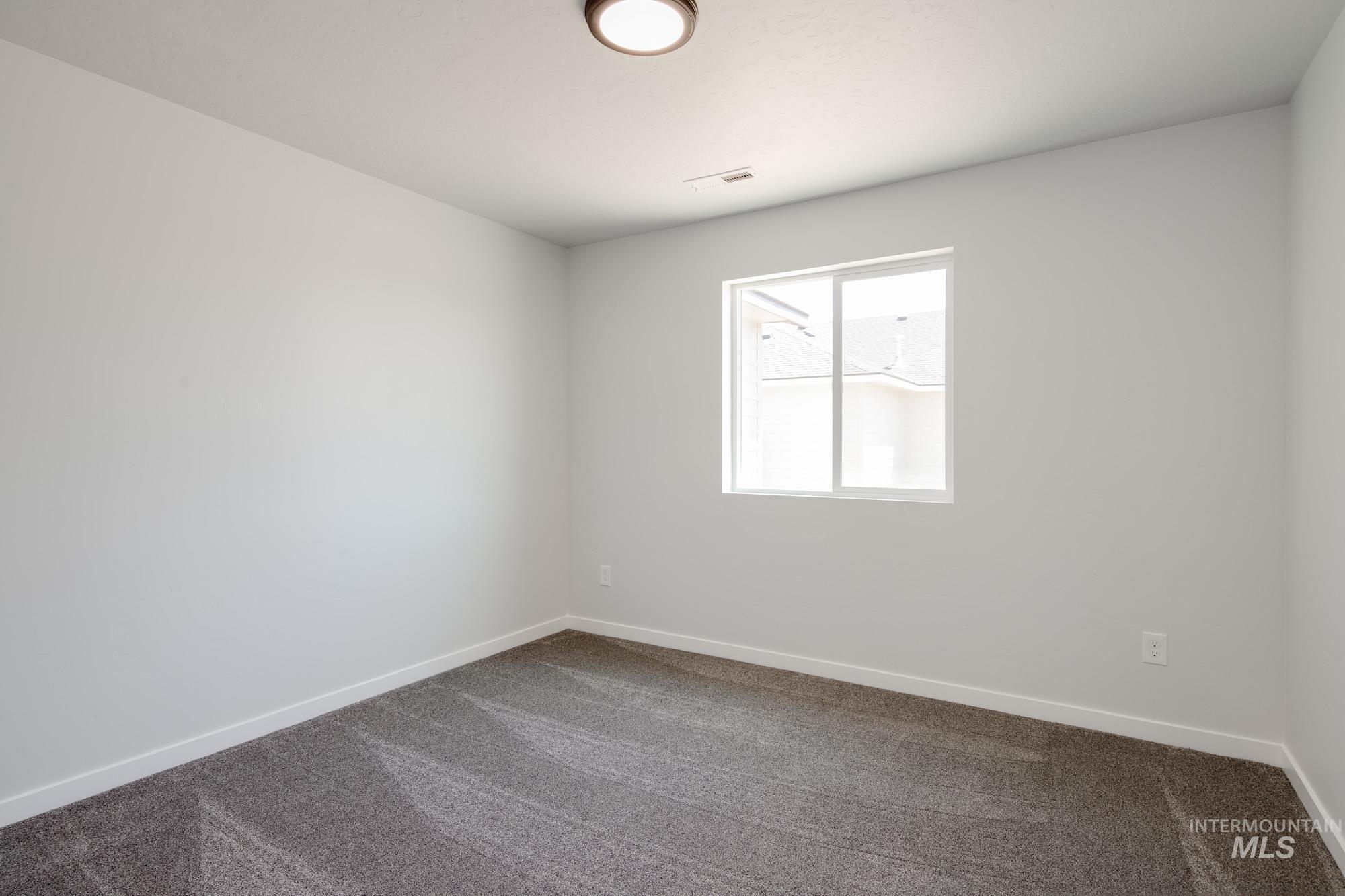 Spare room featuring dark colored carpet