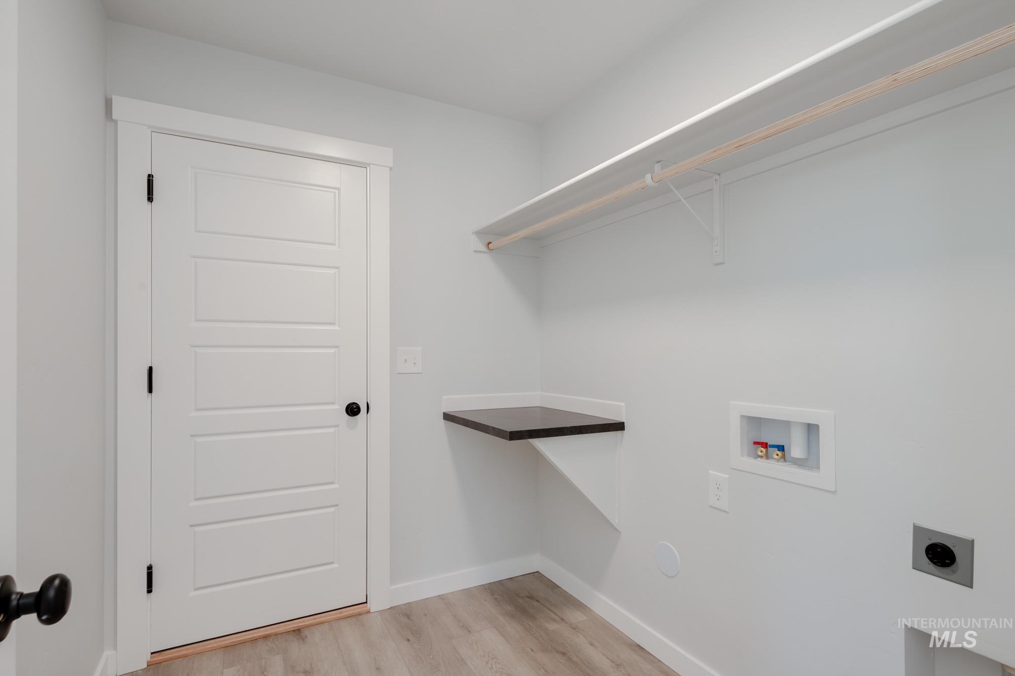 Laundry room with hookup for an electric dryer, hookup for a washing machine, and light wood-style floors