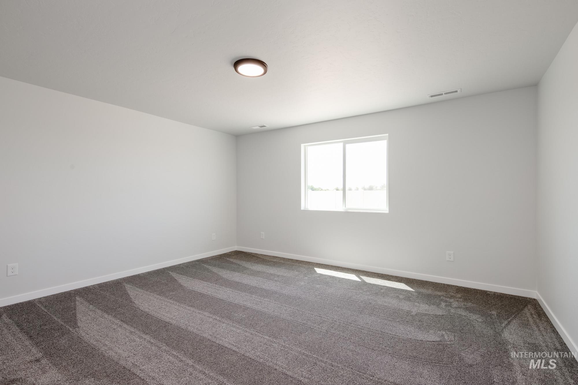 Empty room featuring dark carpet and baseboards