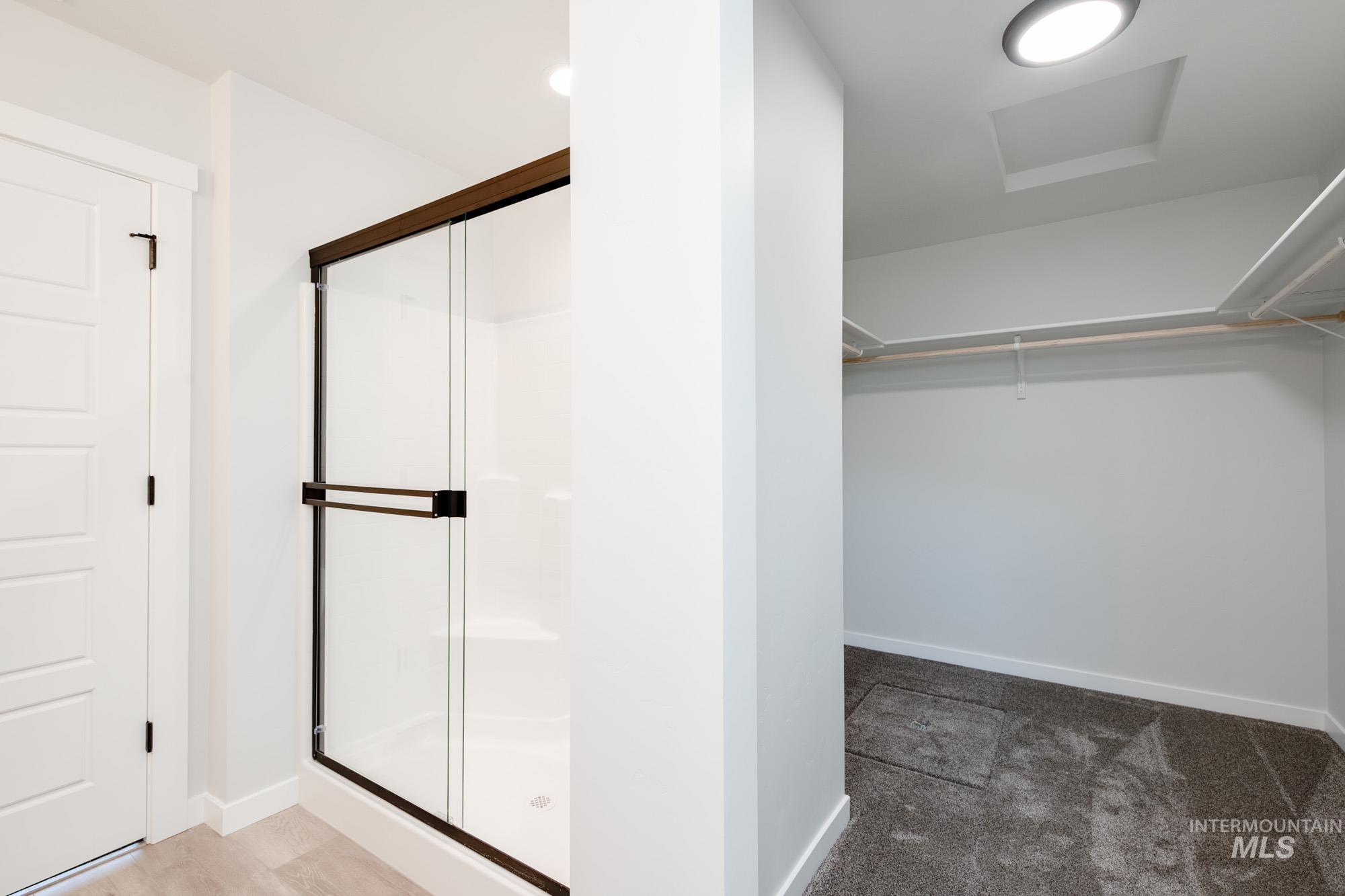 Bathroom featuring a shower stall and a walk in closet