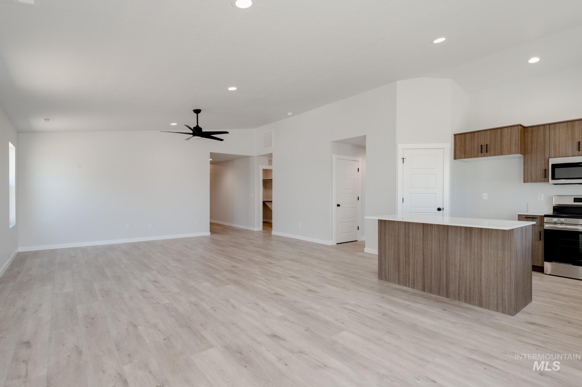Kitchen with stainless steel appliances, light countertops, a kitchen island, lofted ceiling, and ceiling fan