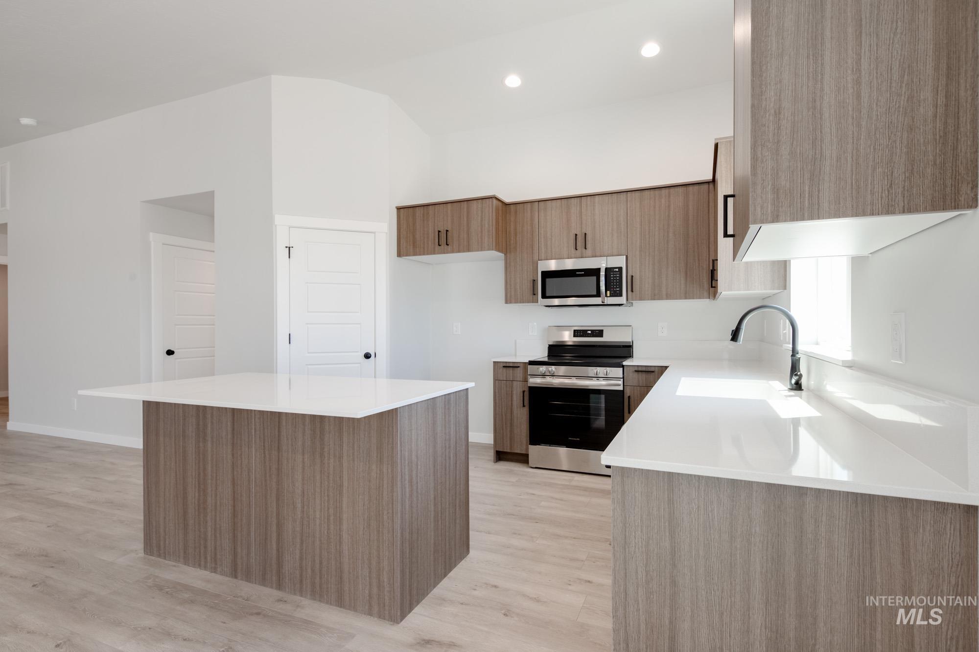 Kitchen with appliances with stainless steel finishes, light wood-style flooring, light countertops, modern cabinets, and recessed lighting