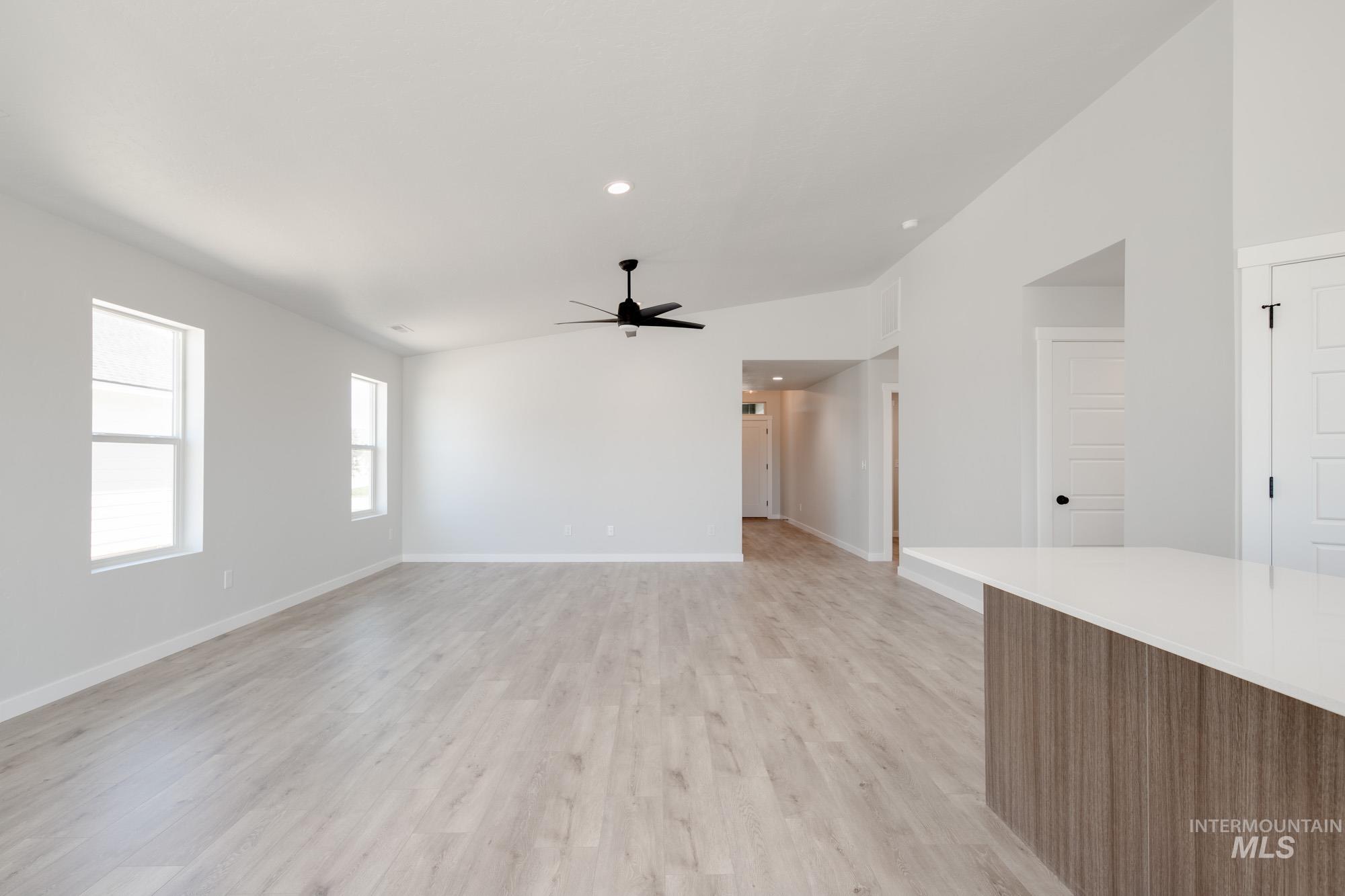 Unfurnished living room featuring a ceiling fan, light wood-style flooring, recessed lighting, and vaulted ceiling