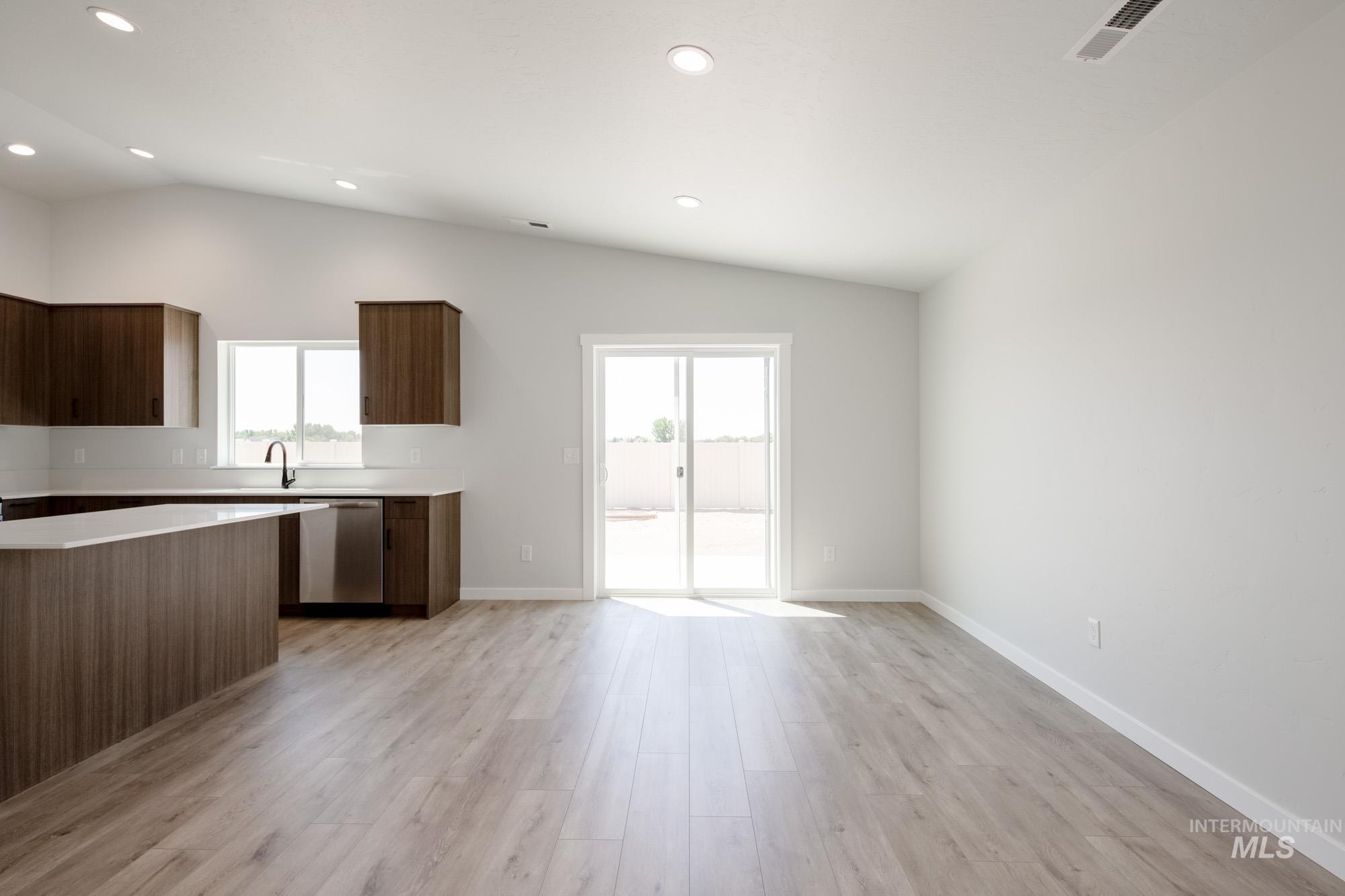 Kitchen featuring vaulted ceiling, light countertops, dishwasher, light wood-type flooring, and recessed lighting