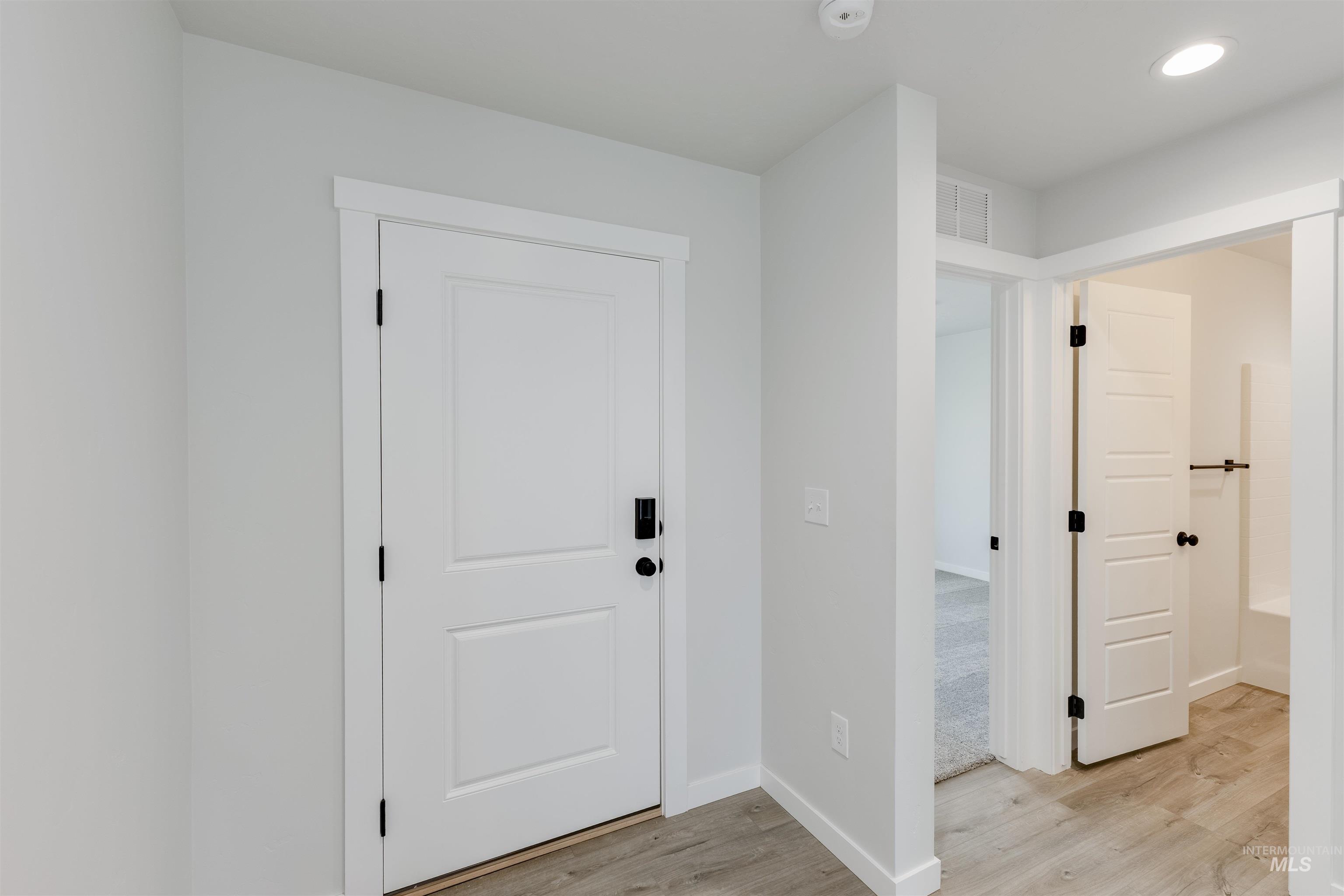 Foyer entrance with light wood-style floors and recessed lighting