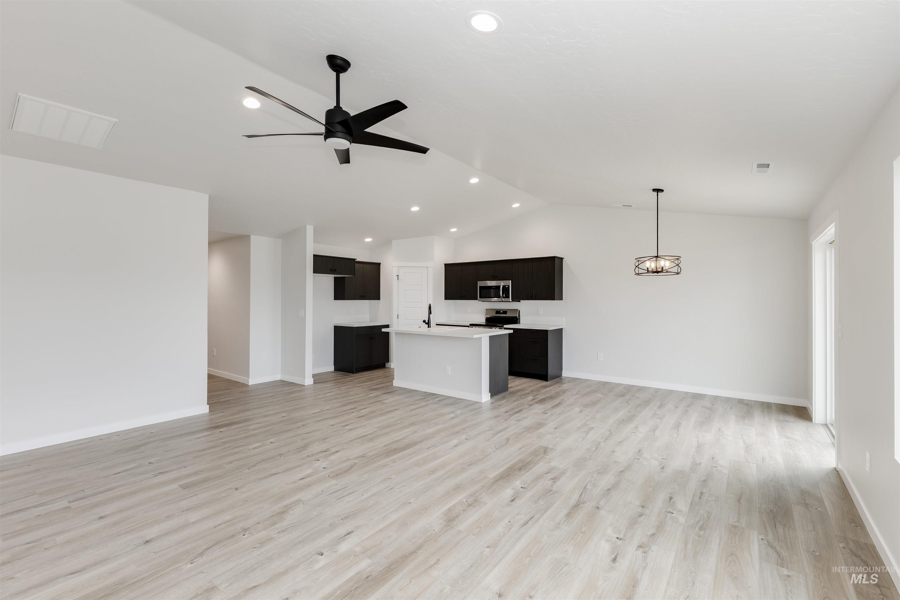 Unfurnished living room with vaulted ceiling, light wood finished floors, ceiling fan, and recessed lighting