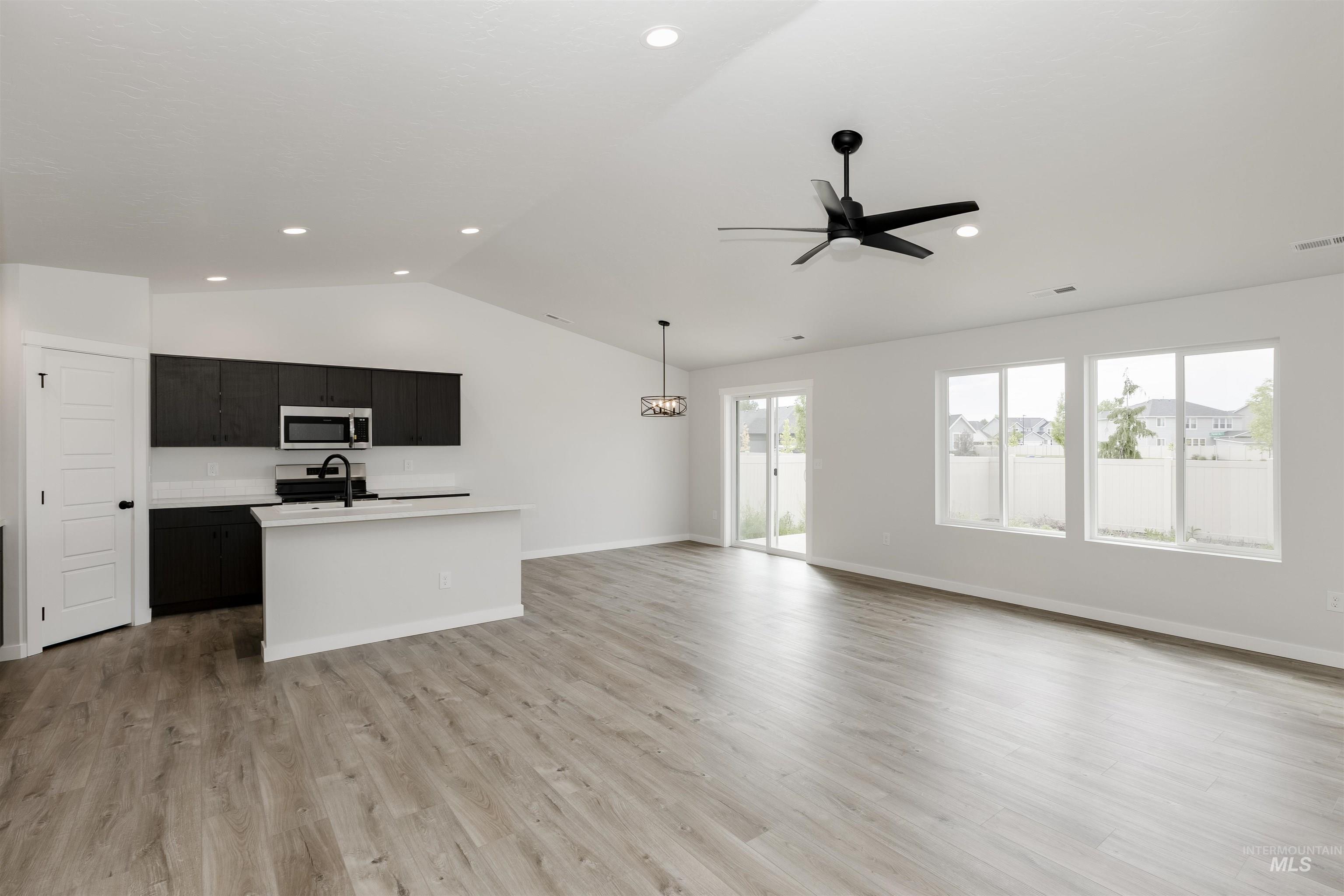 Unfurnished living room with lofted ceiling, light wood-style flooring, ceiling fan, and recessed lighting