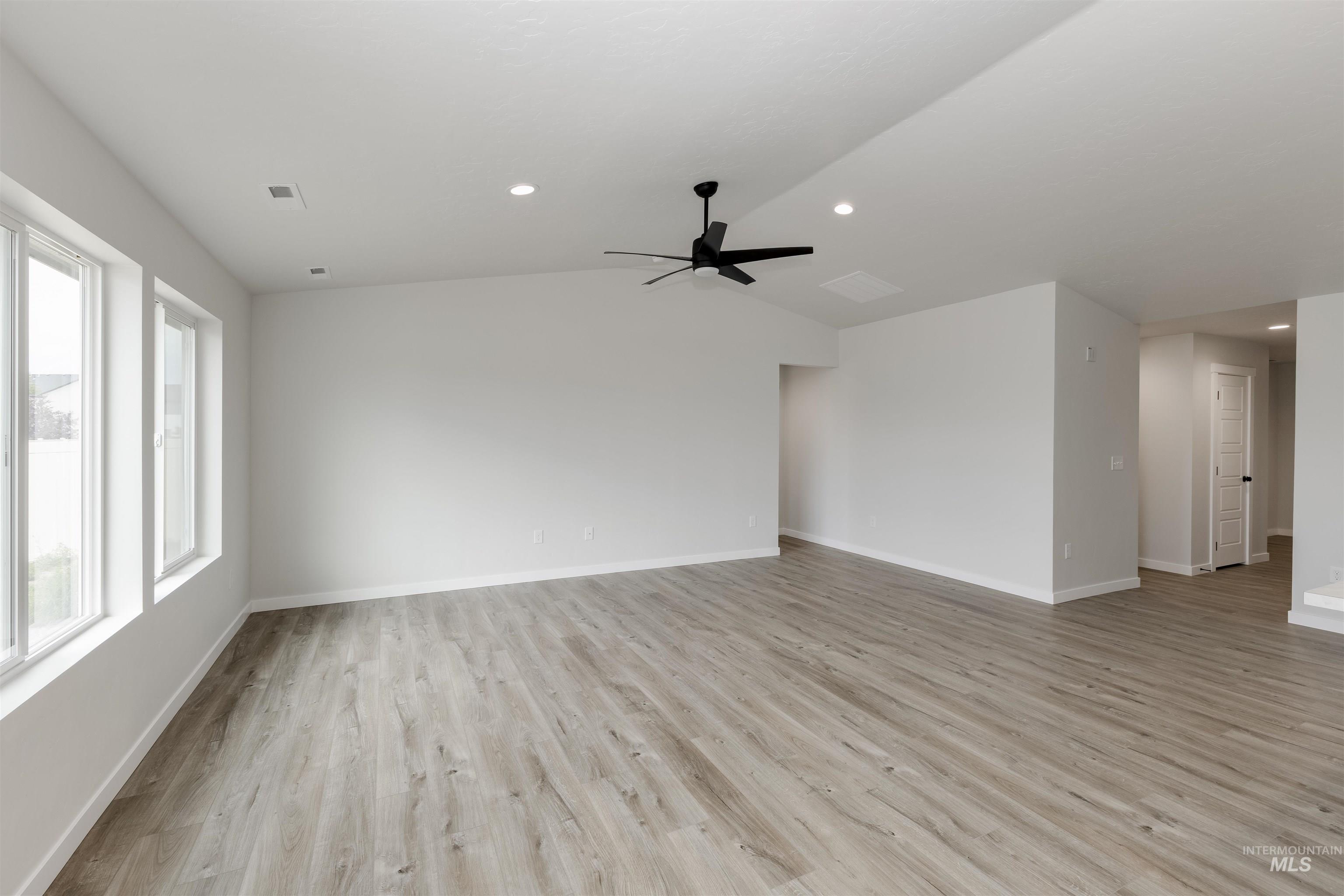 Unfurnished living room with lofted ceiling, light wood-type flooring, ceiling fan, and recessed lighting