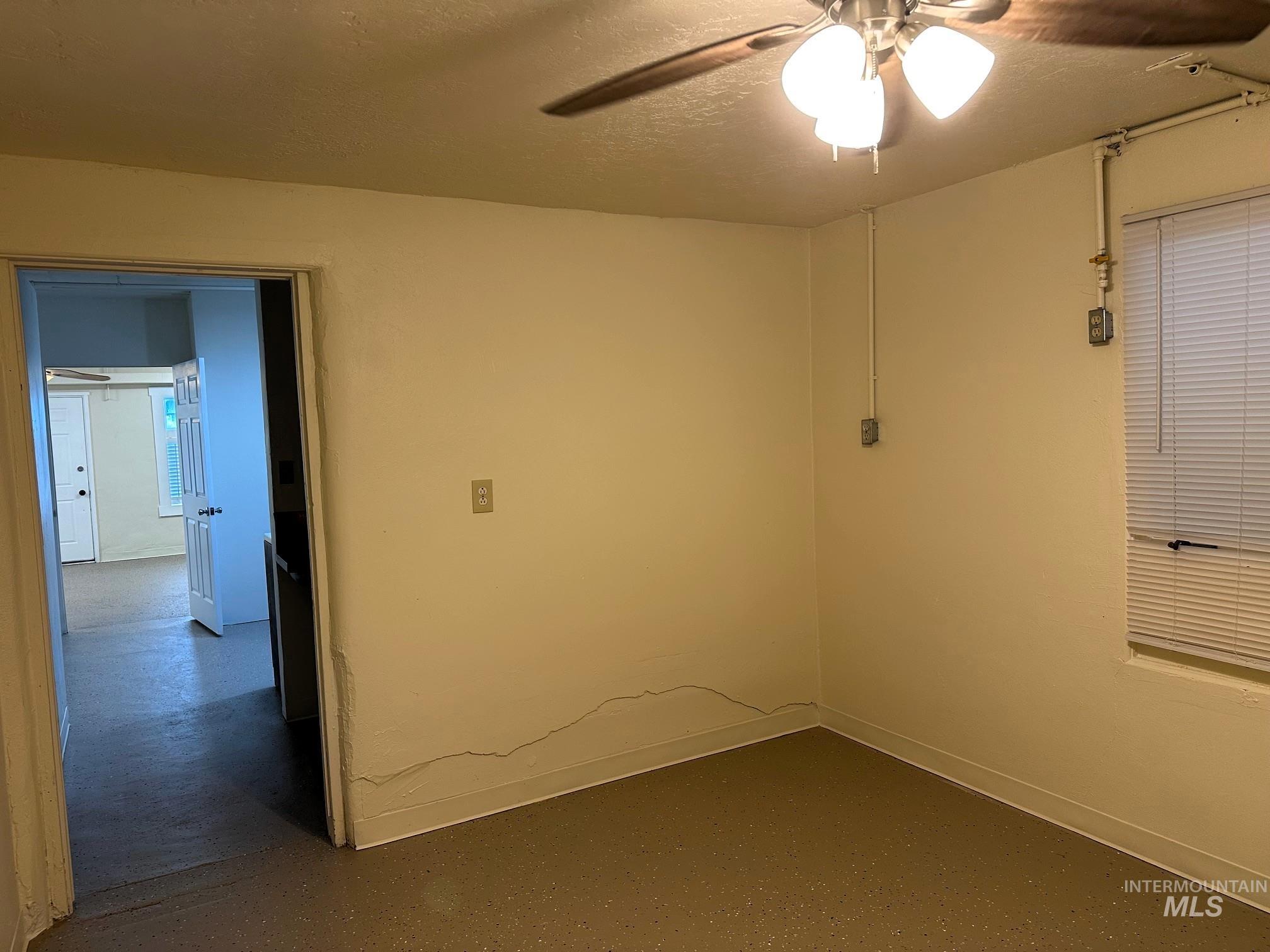 Unfurnished room featuring a textured ceiling, a ceiling fan, and finished concrete floors
