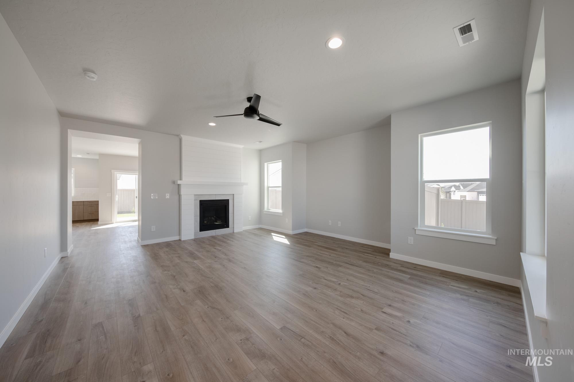 Unfurnished living room featuring a ceiling fan, recessed lighting, light wood-type flooring, and healthy amount of natural light