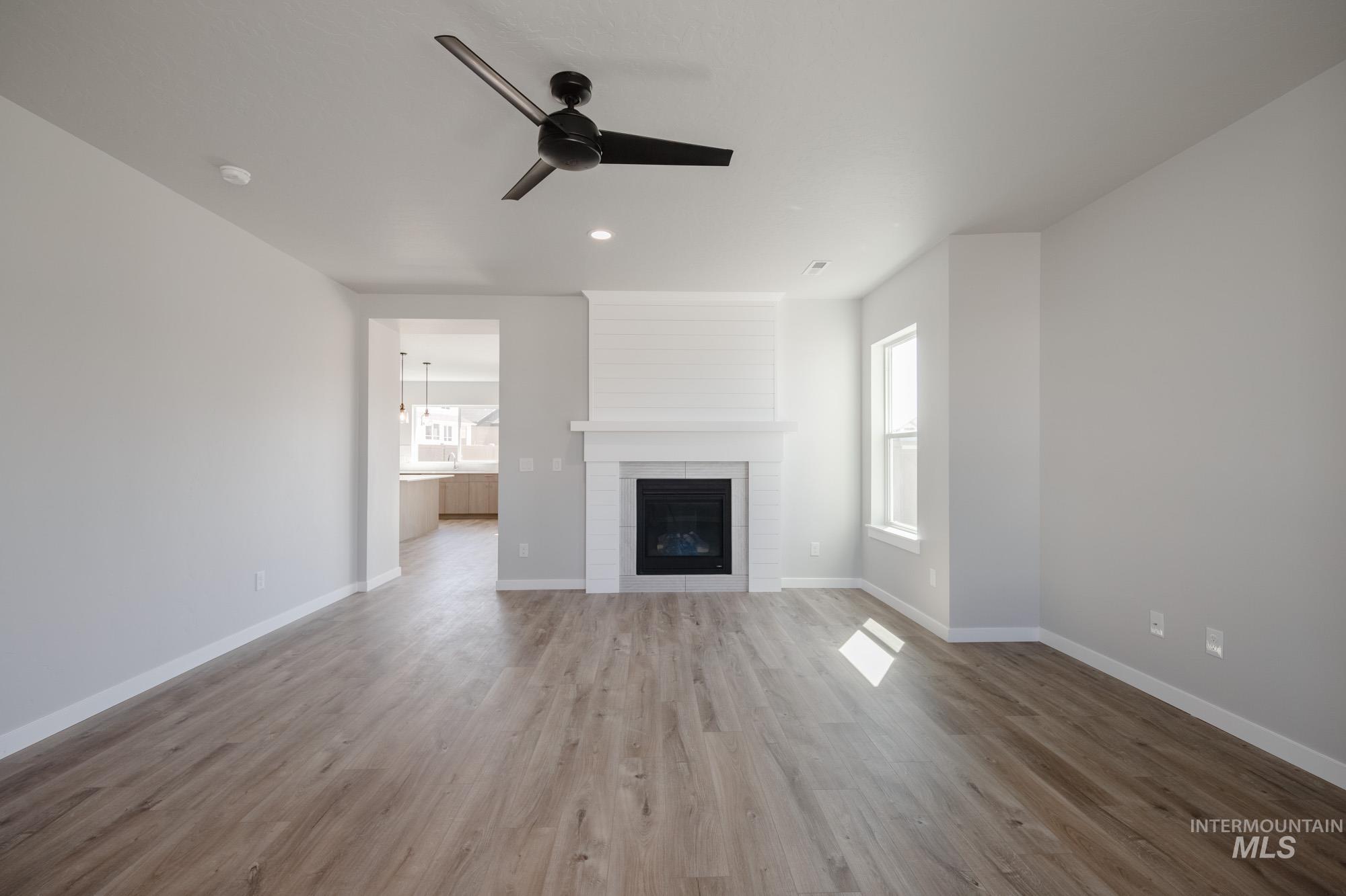 Unfurnished living room with plenty of natural light, light wood-type flooring, a fireplace, a ceiling fan, and recessed lighting